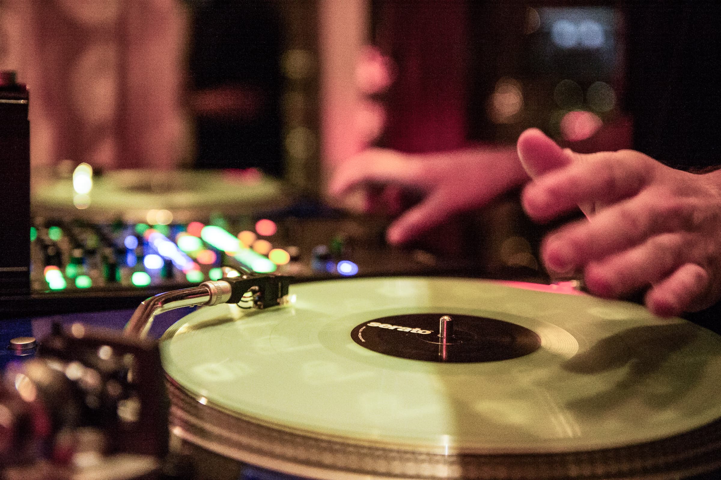 Close view of a hand reaching for a turntable during a set
