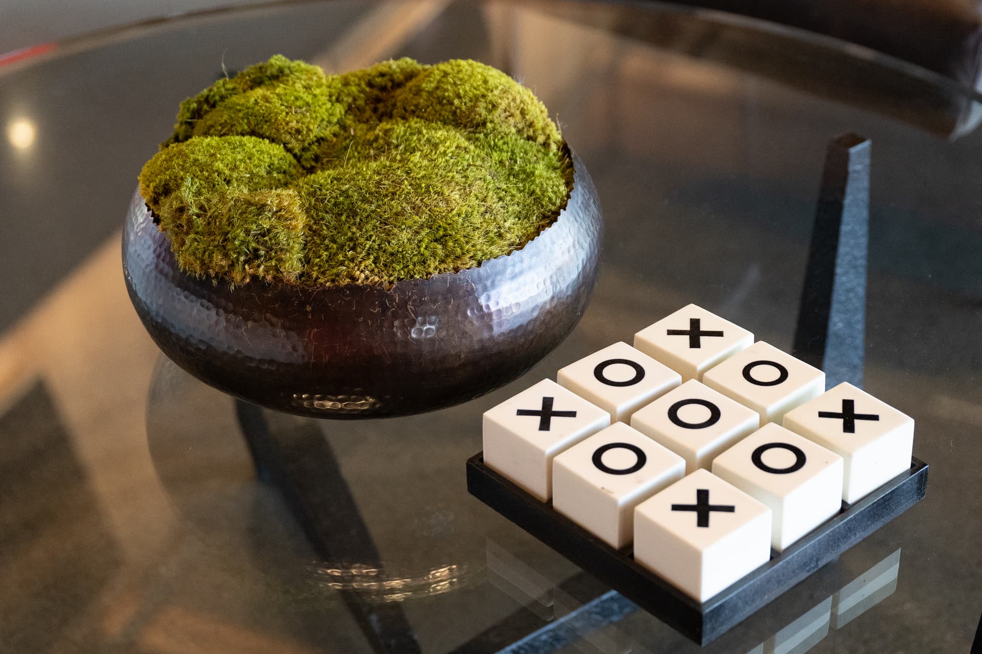 Tic-tac-toe board and a bowl of green moss on a glass lounge table at Ferrari Corso Pilota