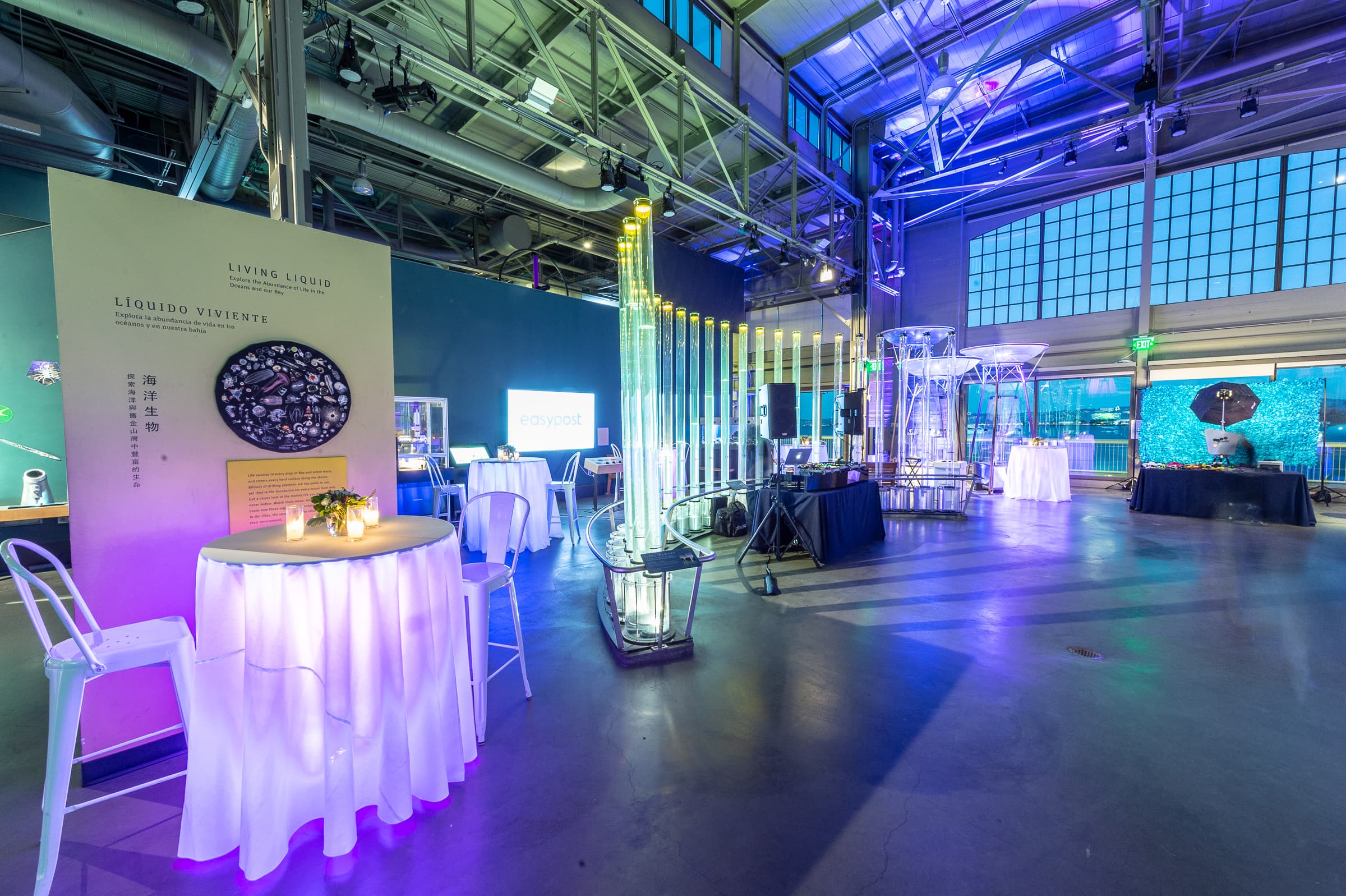 High tables and blue uplighting in a hangar-style venue