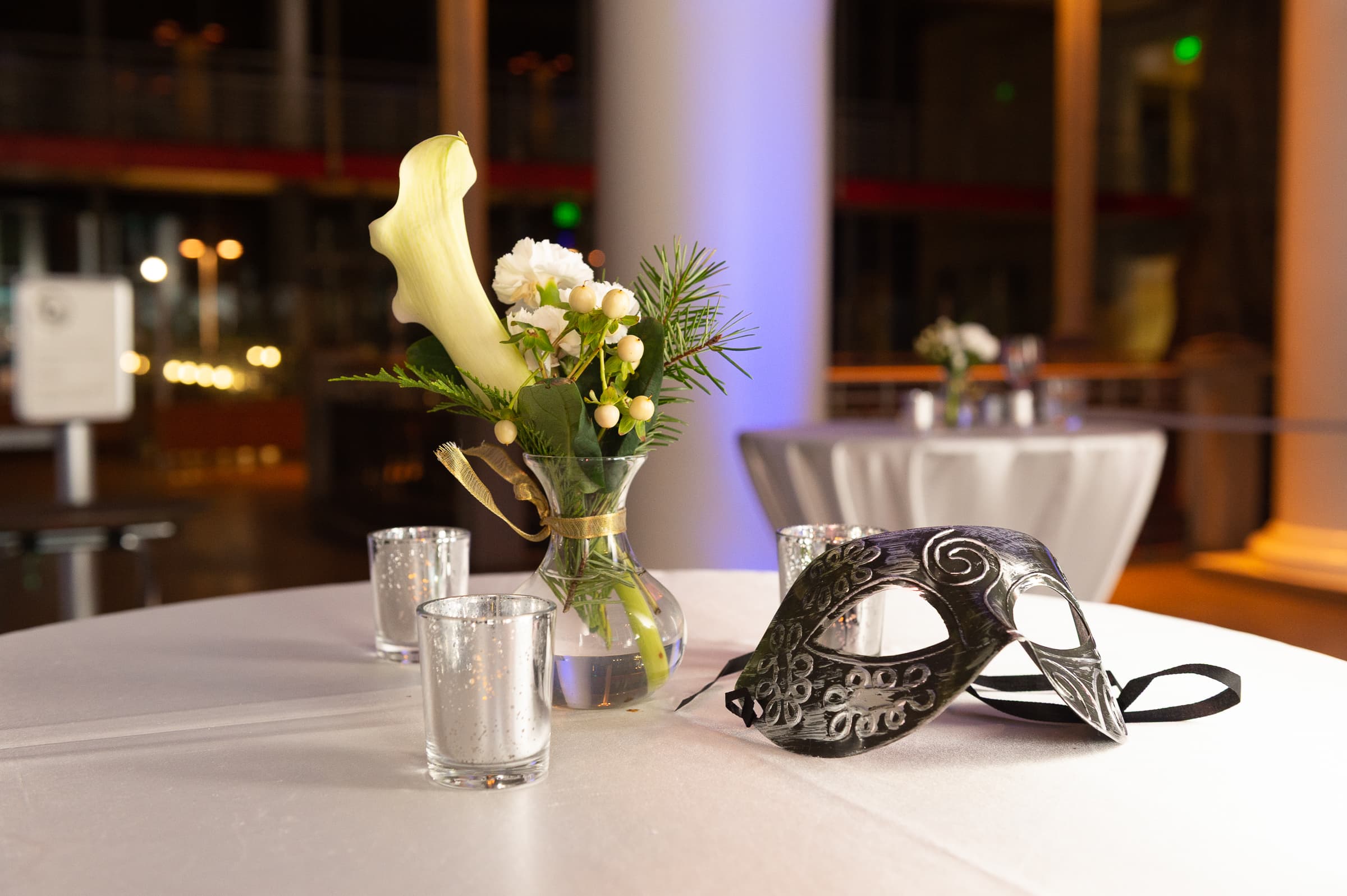 Masquerade masks resting on a table beside white florals