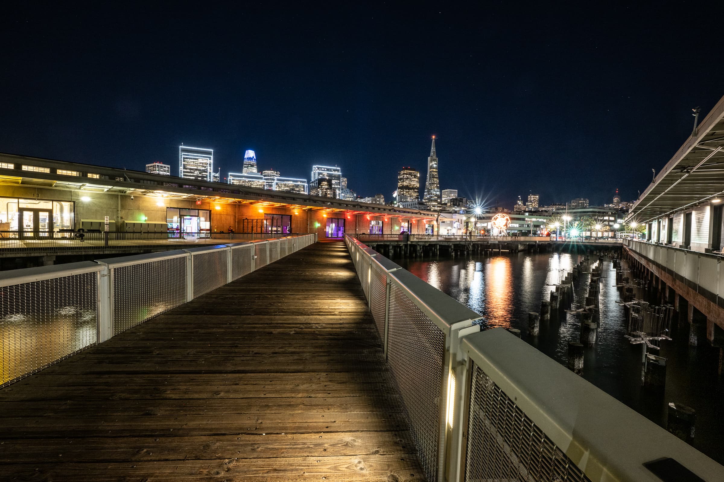 Pier at night with the city skyline reflected on the water
