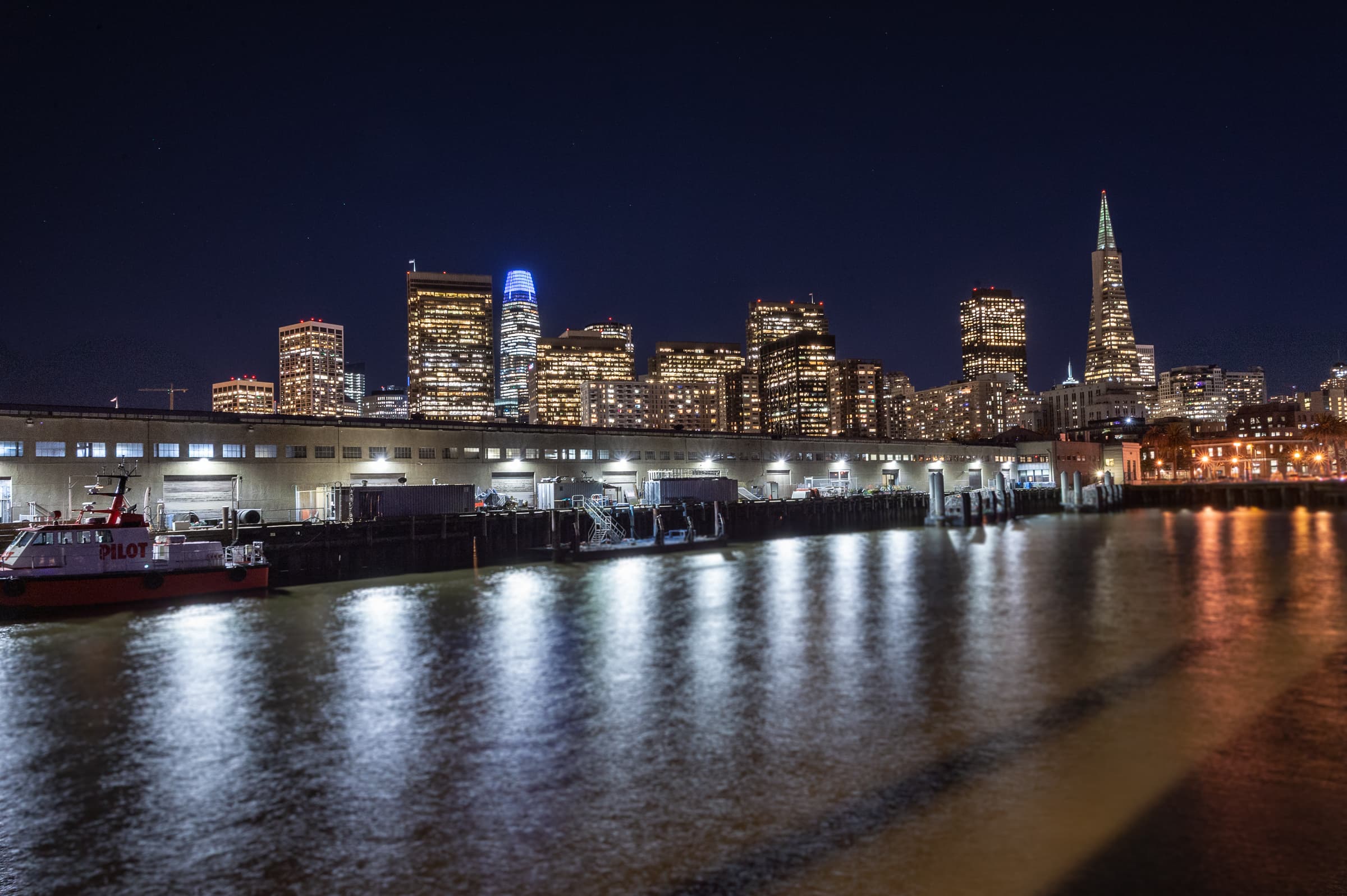 City skyline after dark seen across the water from a venue