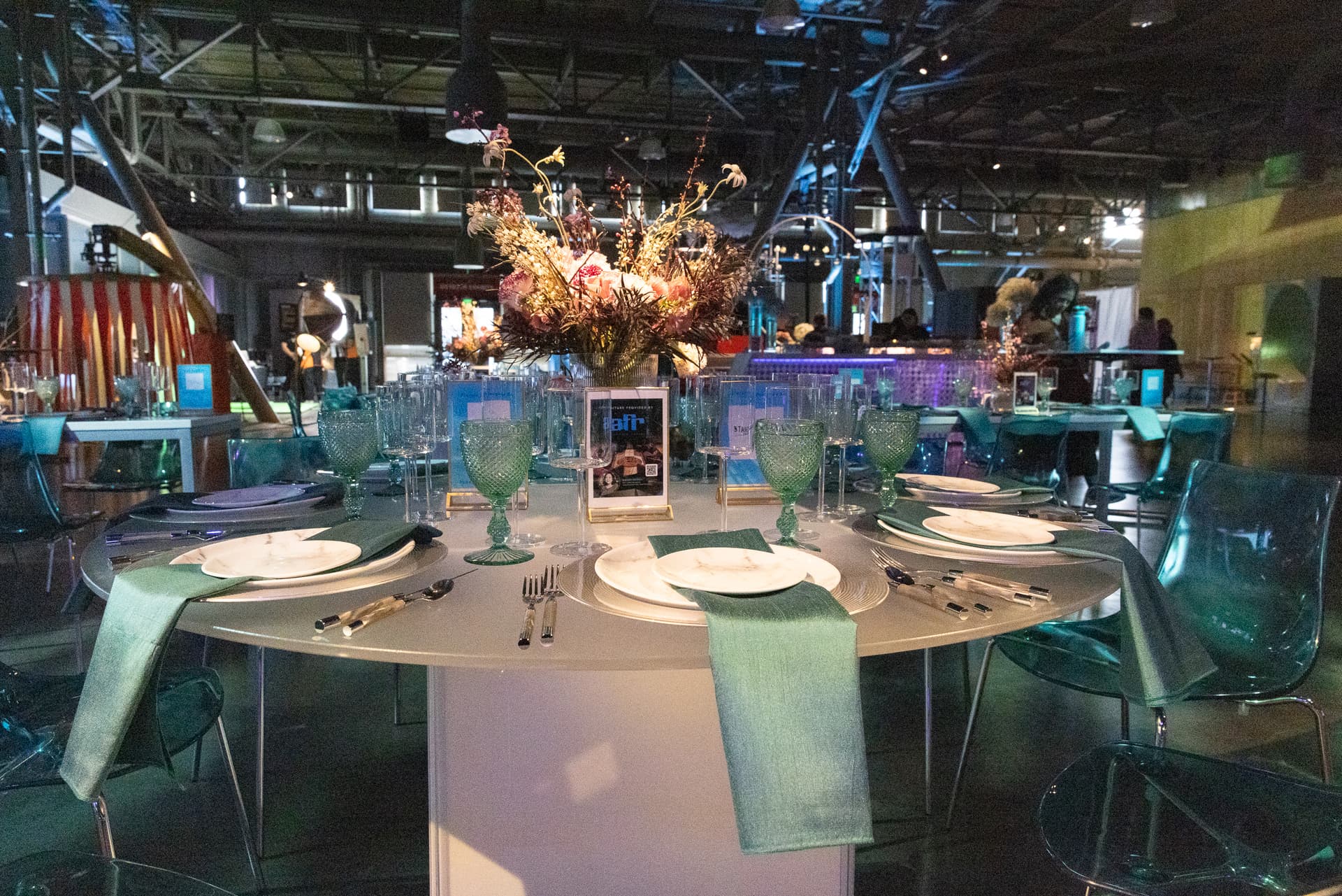 Place setting and floral centrepiece in a teal-lit room
