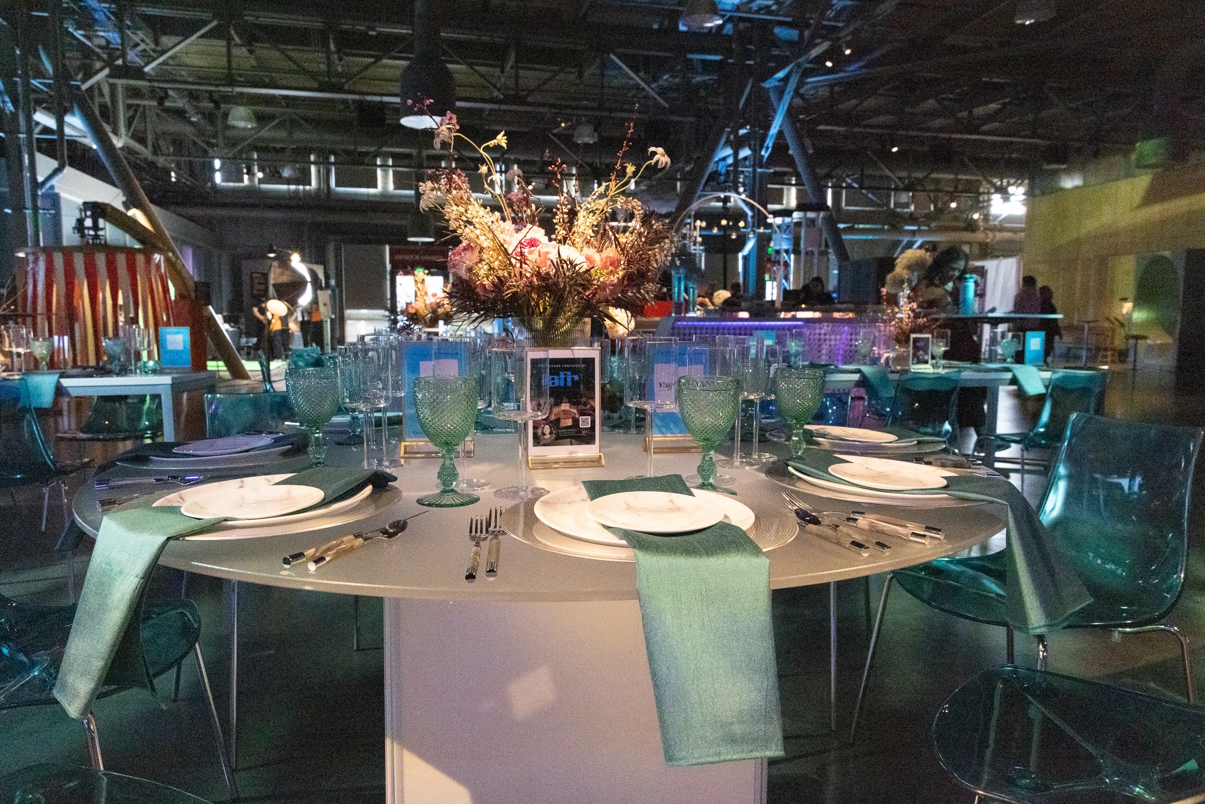 Place setting and floral centrepiece in a teal-lit room