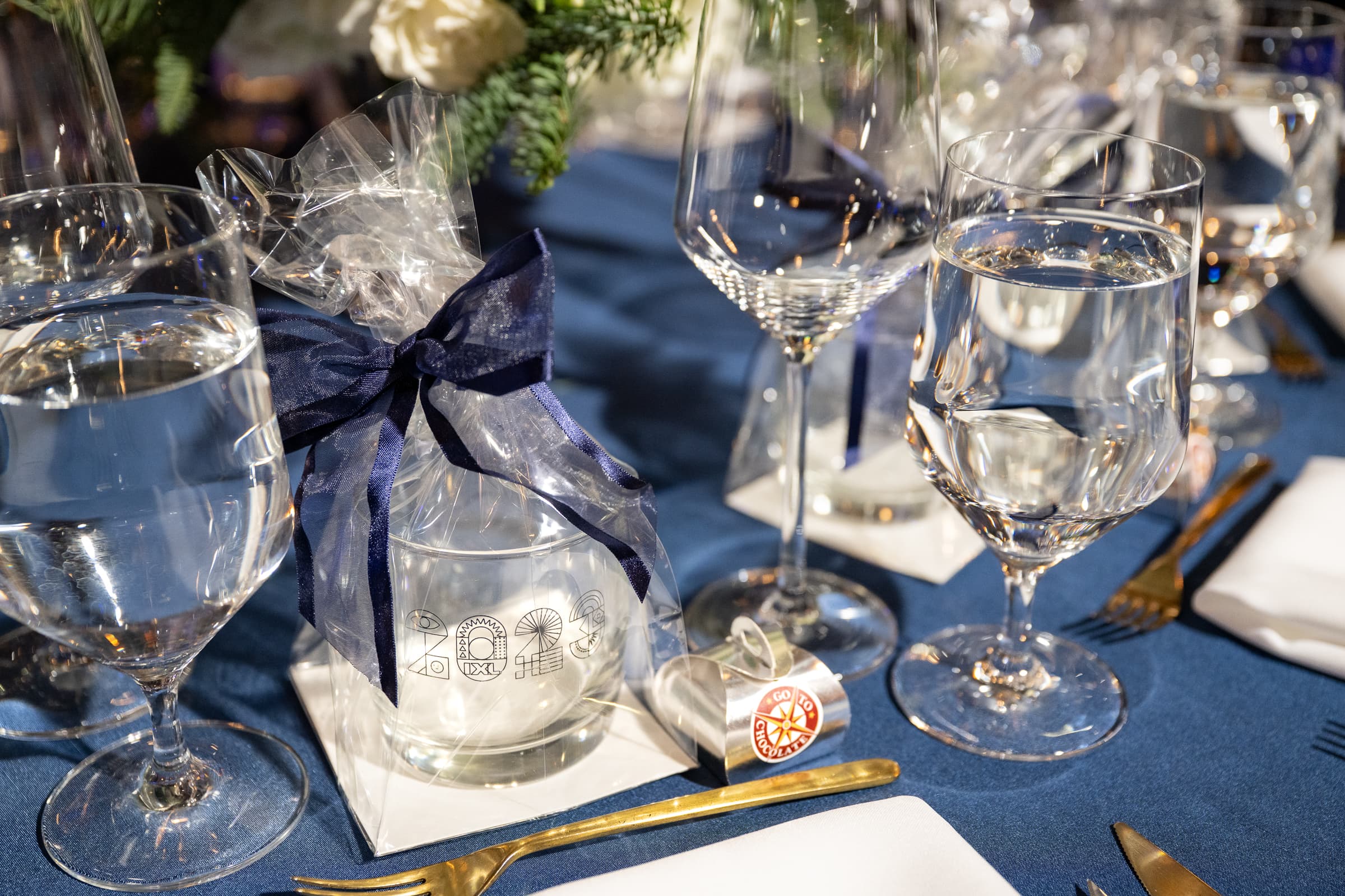 Place setting detail with navy ribbon, glassware and a wrapped favour