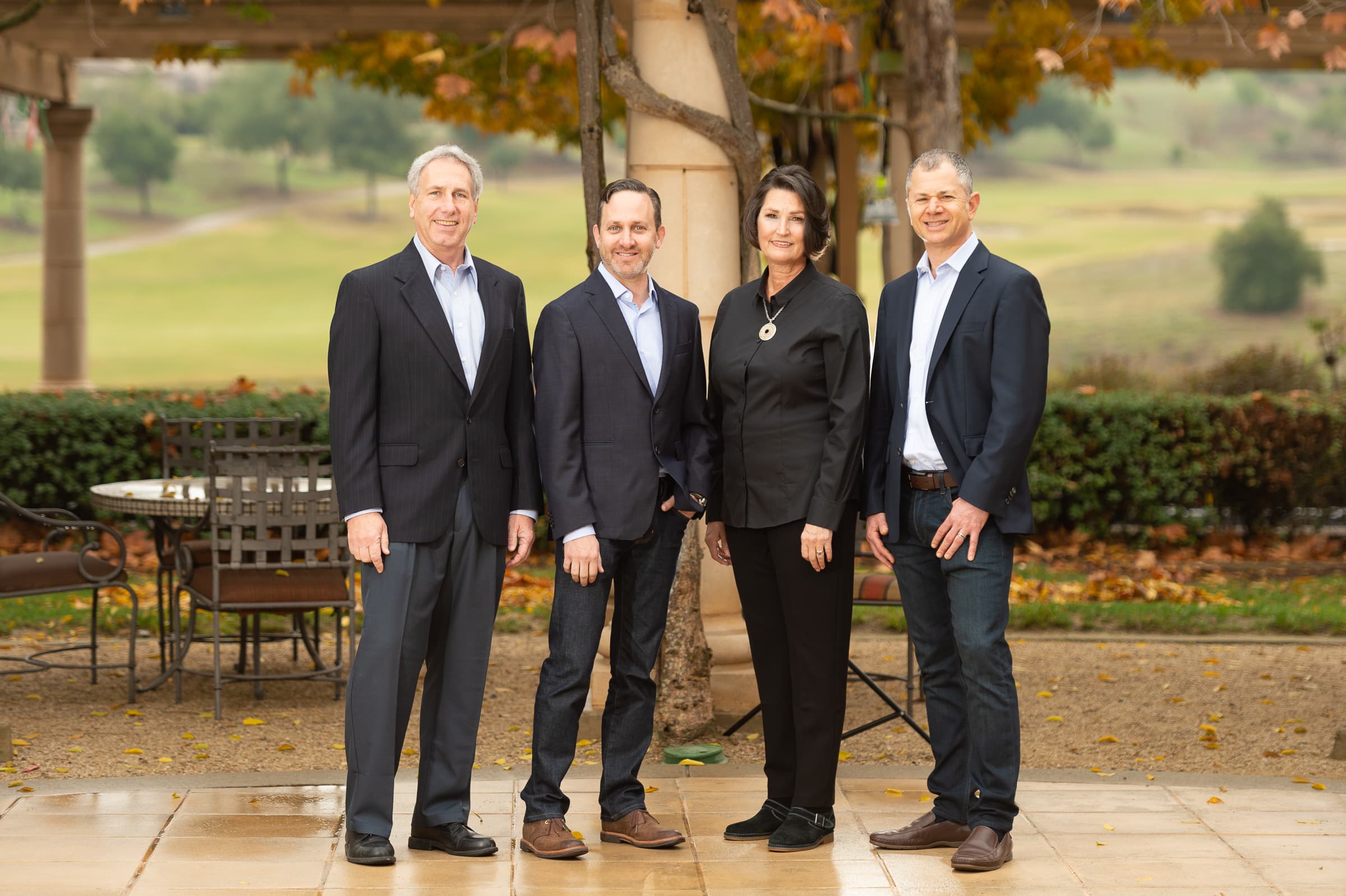 Four executives photographed together outdoors on a clubhouse terrace