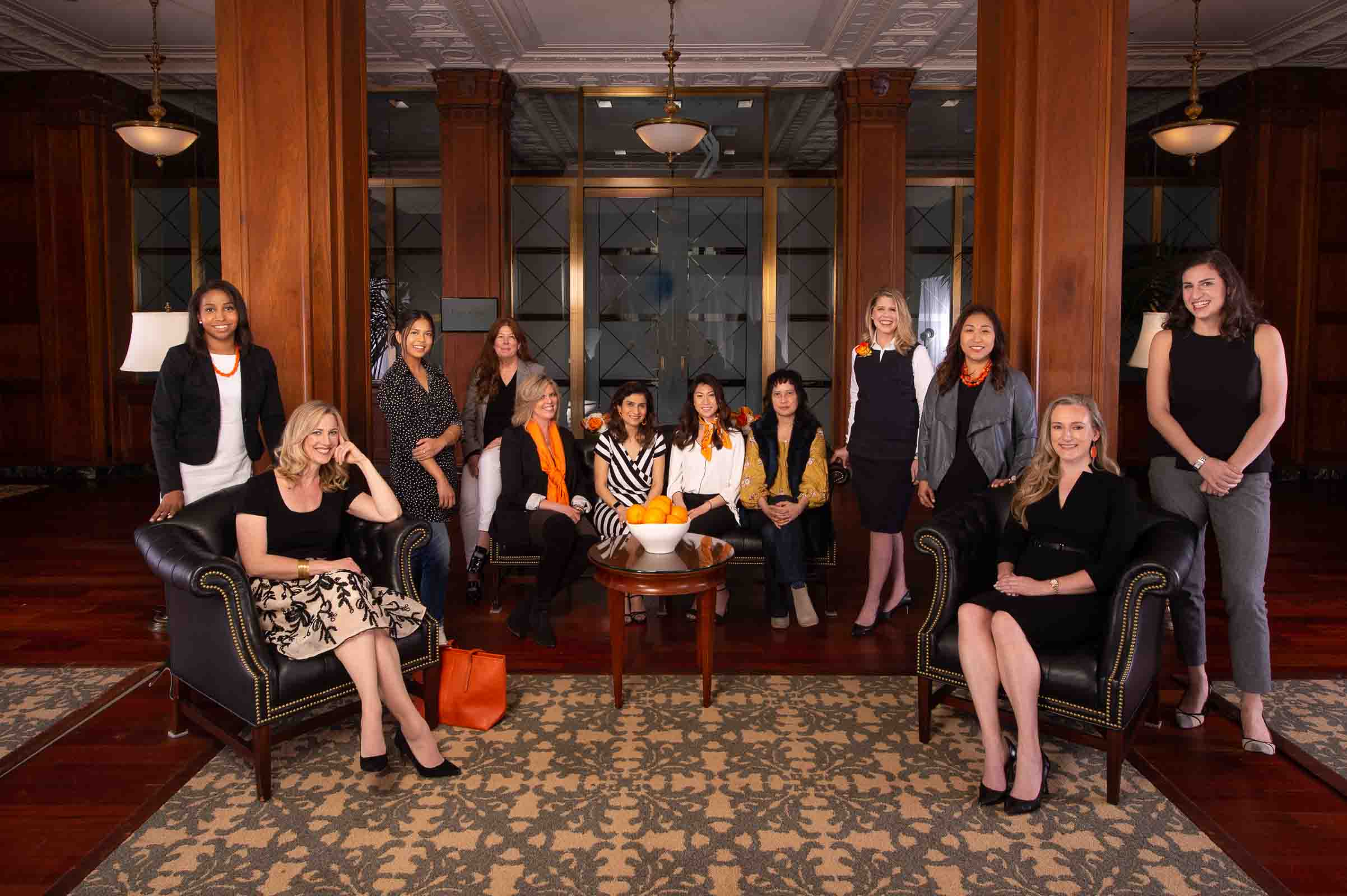 Professional women executives team portrait with coordinated styling in elegant wood-paneled lobby