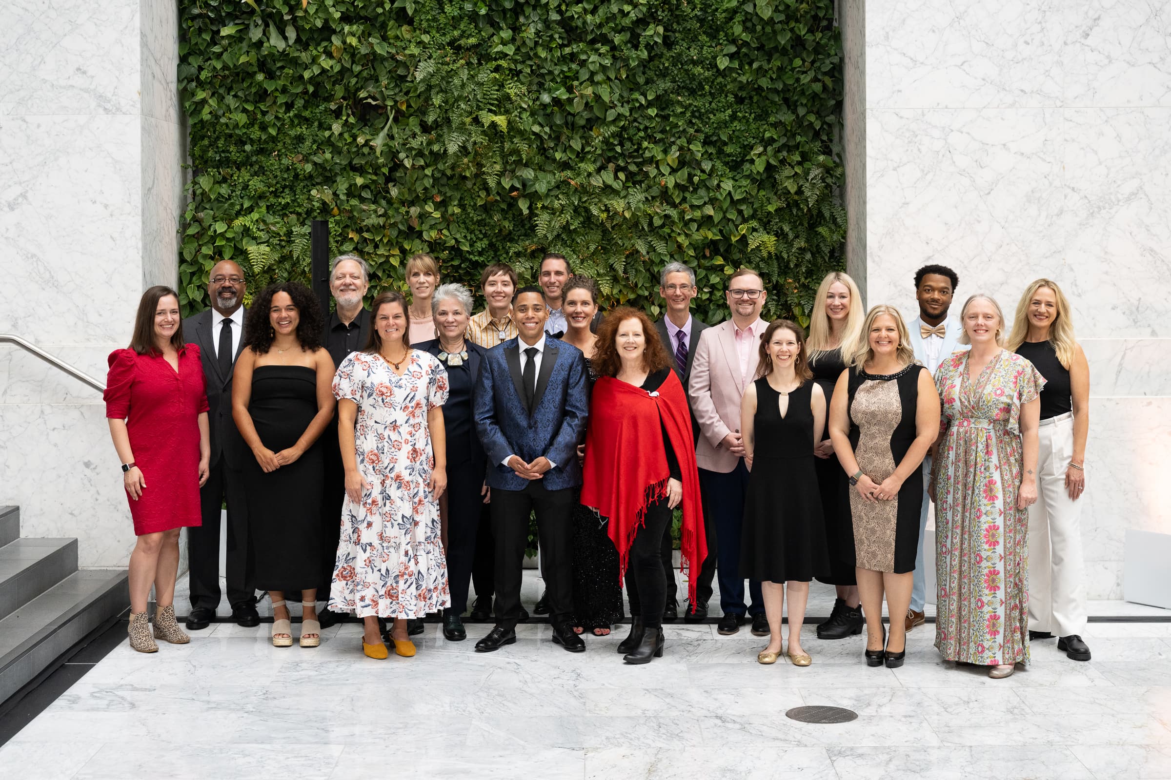 Full team photographed together in front of a living hedge wall