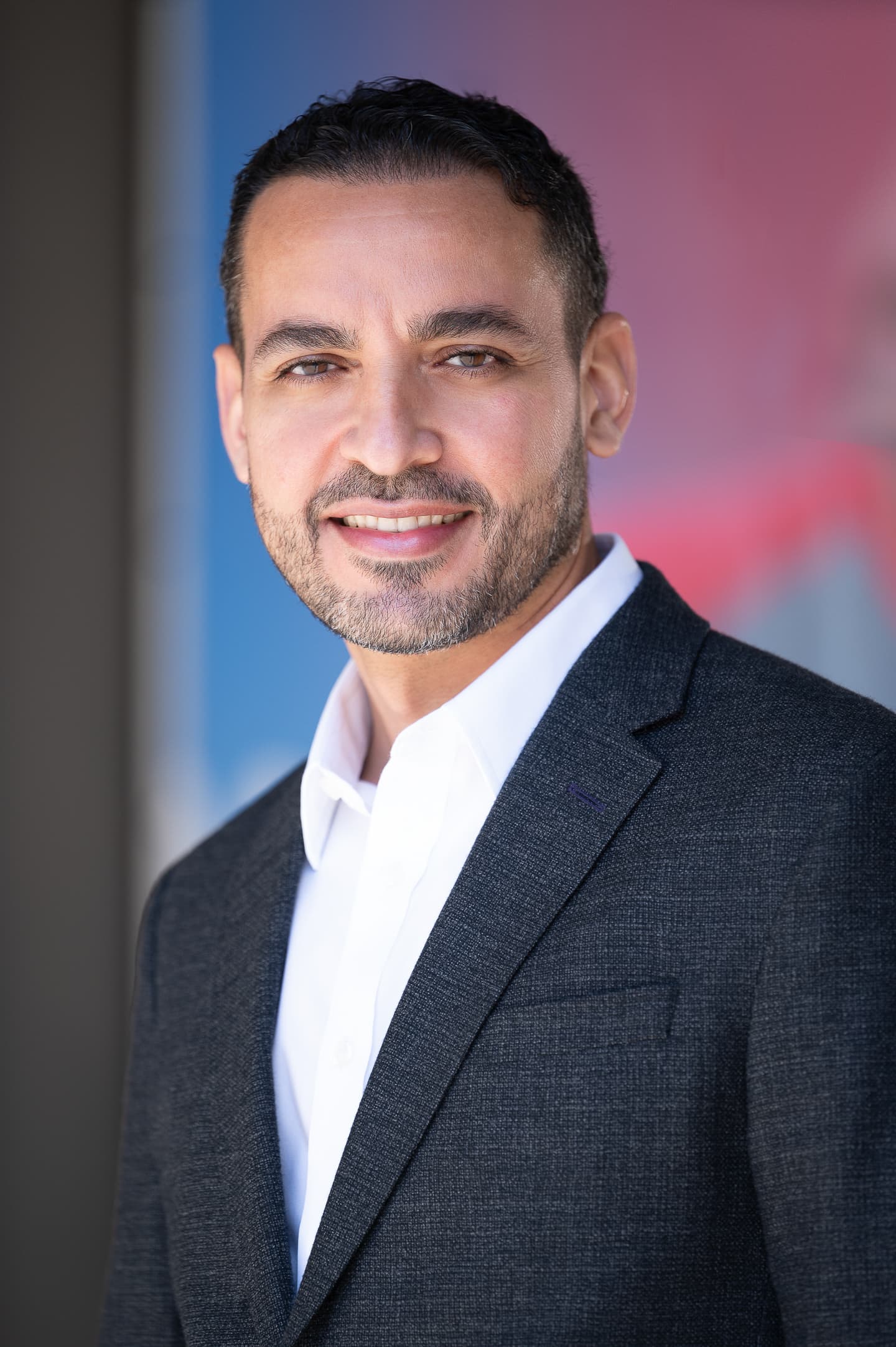 Professional headshot with blue and pink gradient backdrop