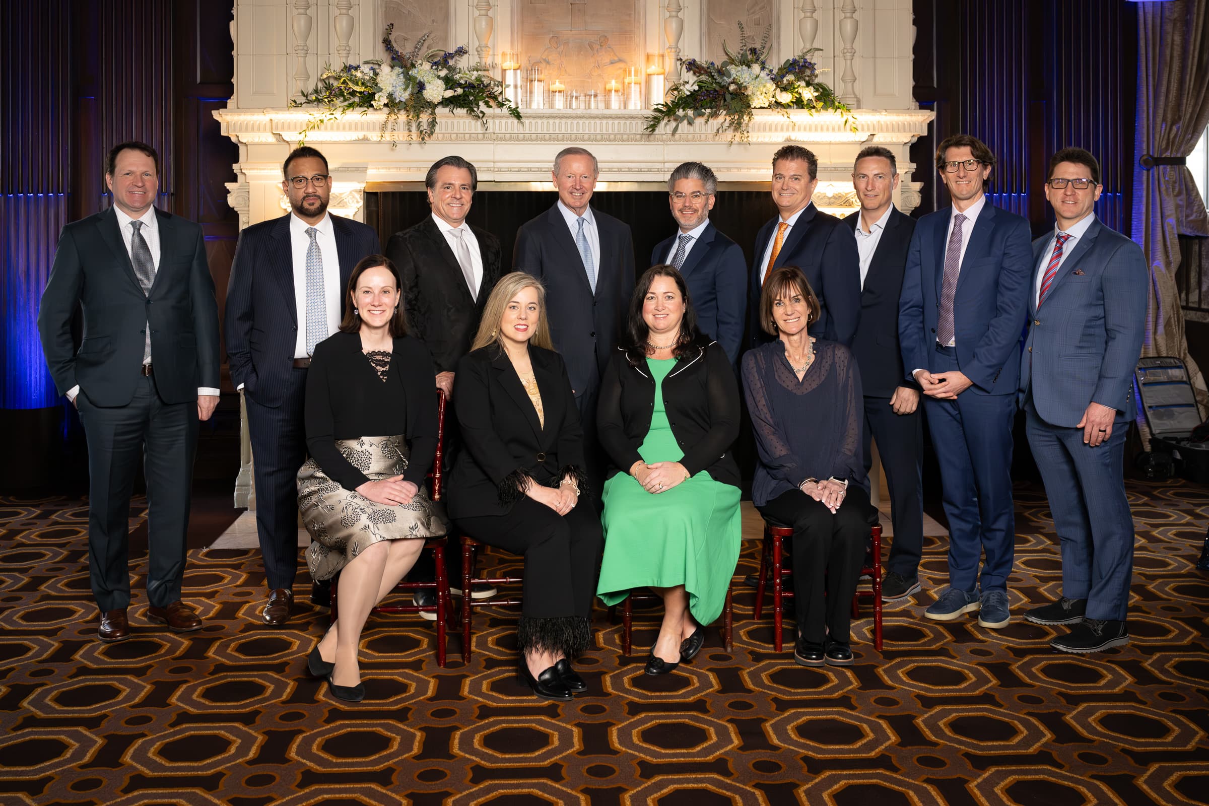 Leadership team photographed together in front of a ballroom fireplace