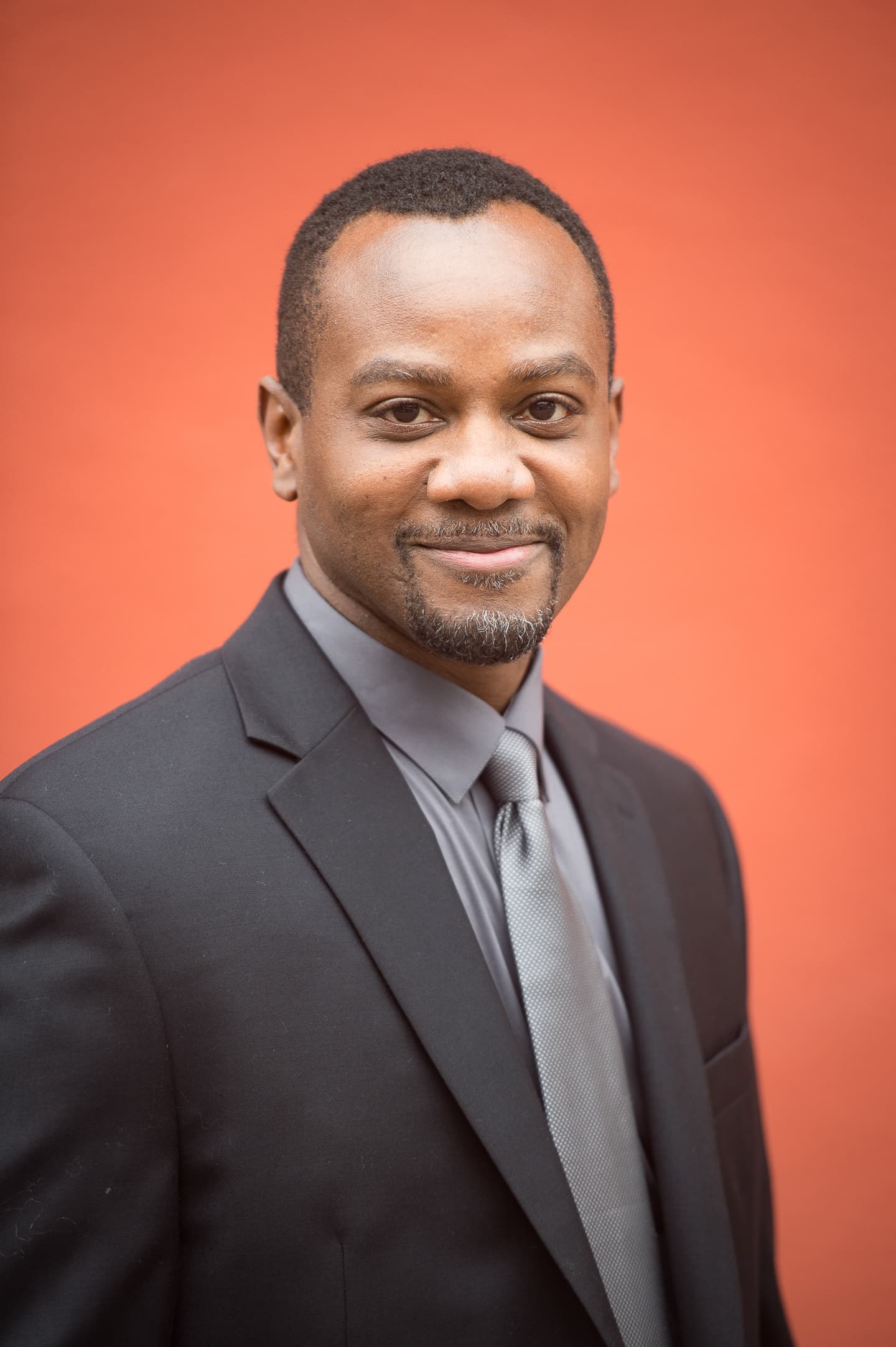 Professional portrait against coral-colored background