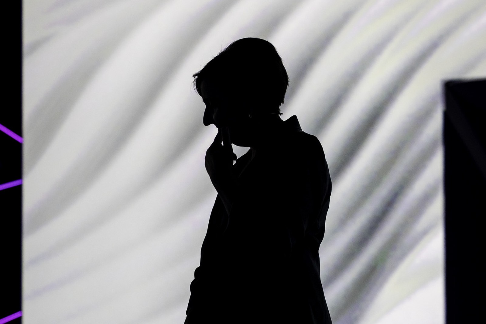 Executive silhouette in profile against a massive curved LED keynote backdrop