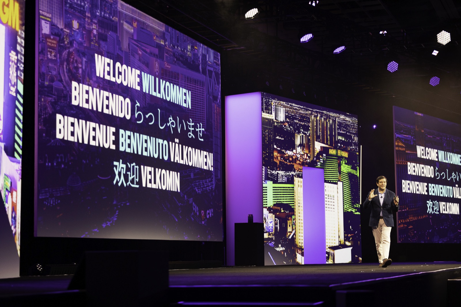 Executive walking a high-production keynote stage flanked by large LED screens