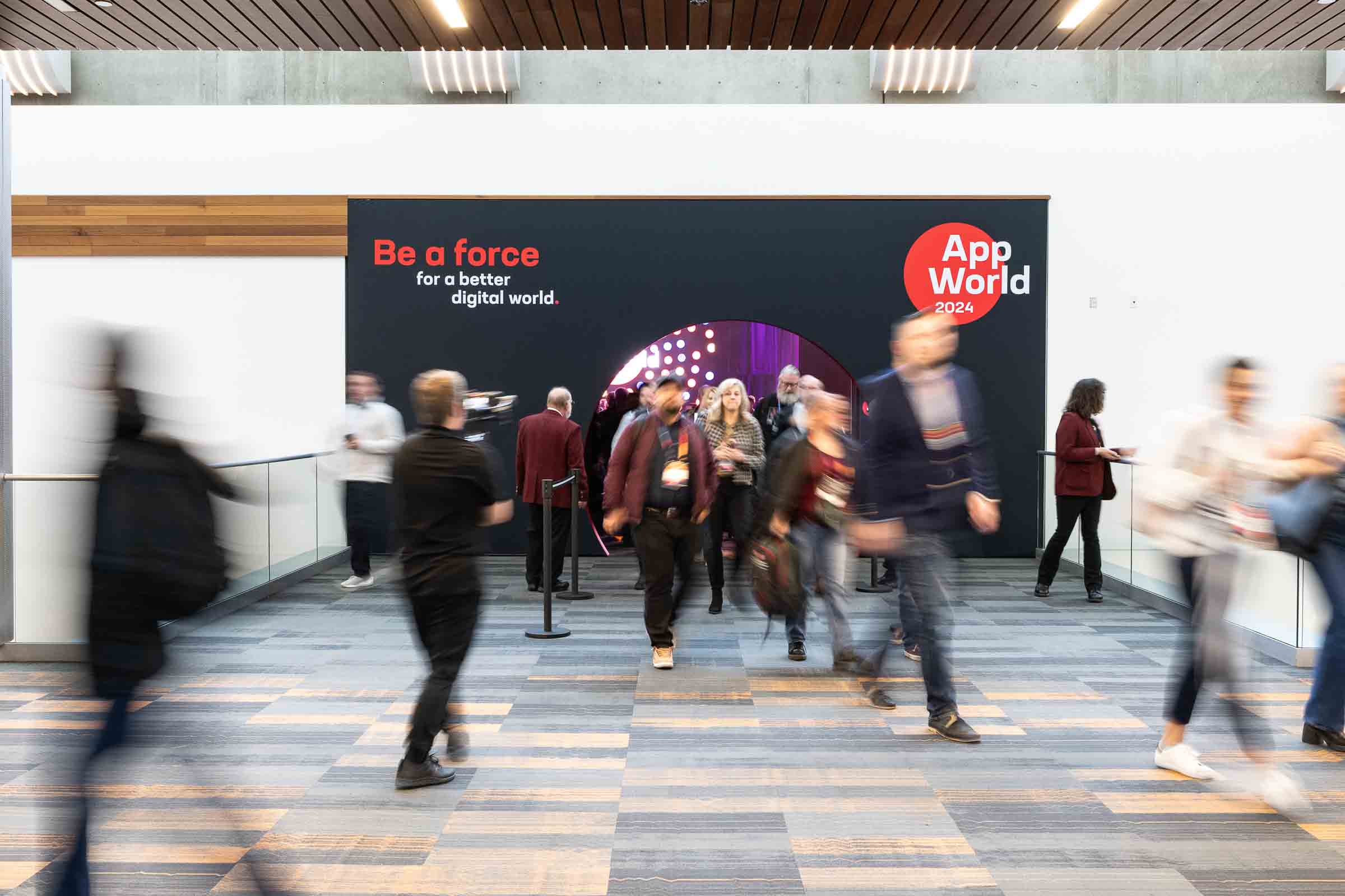 Motion-blurred attendees entering a branded keynote hall at a corporate technology conference