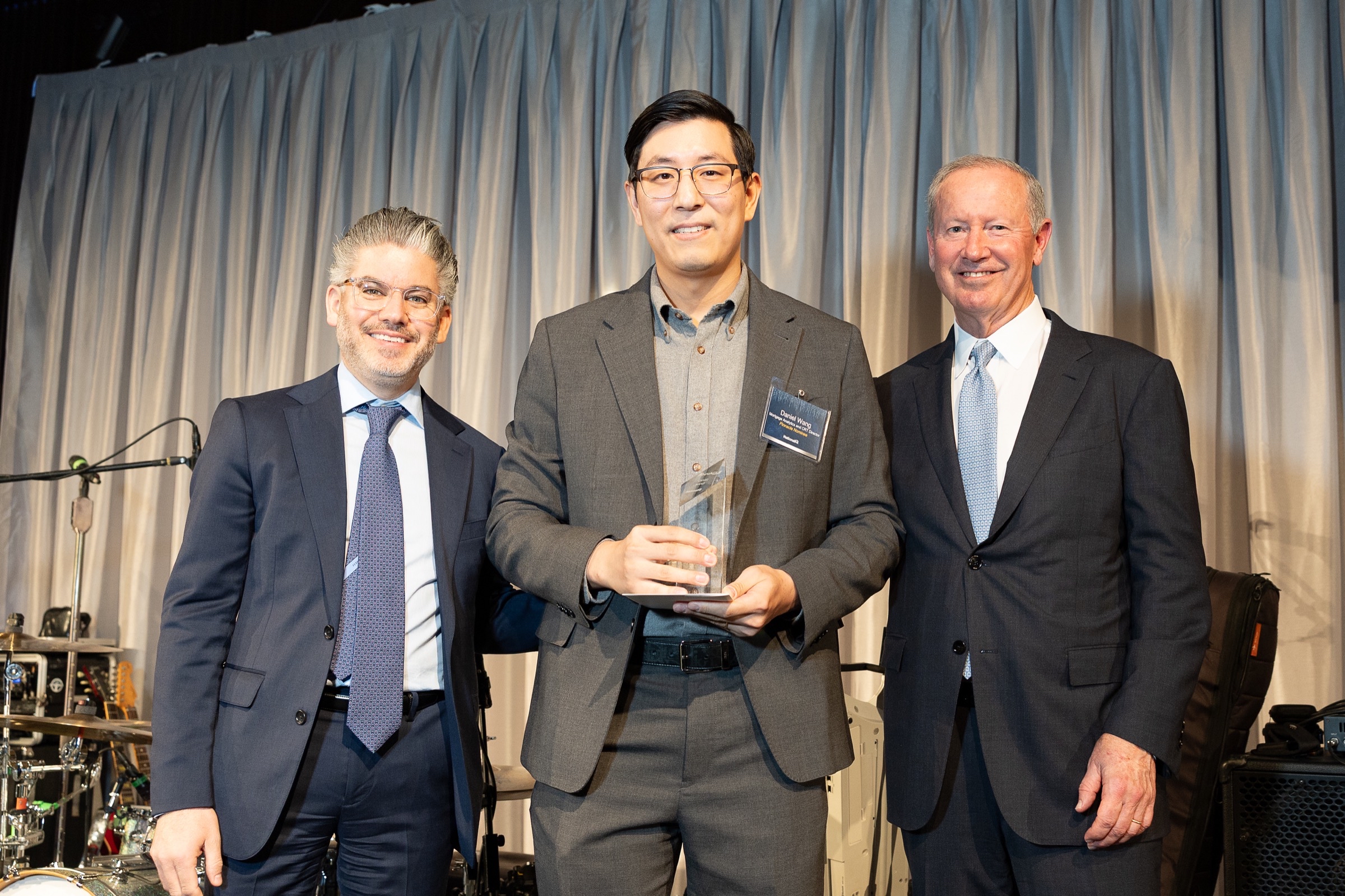 Award recipient on stage with presenters during an awards presentation