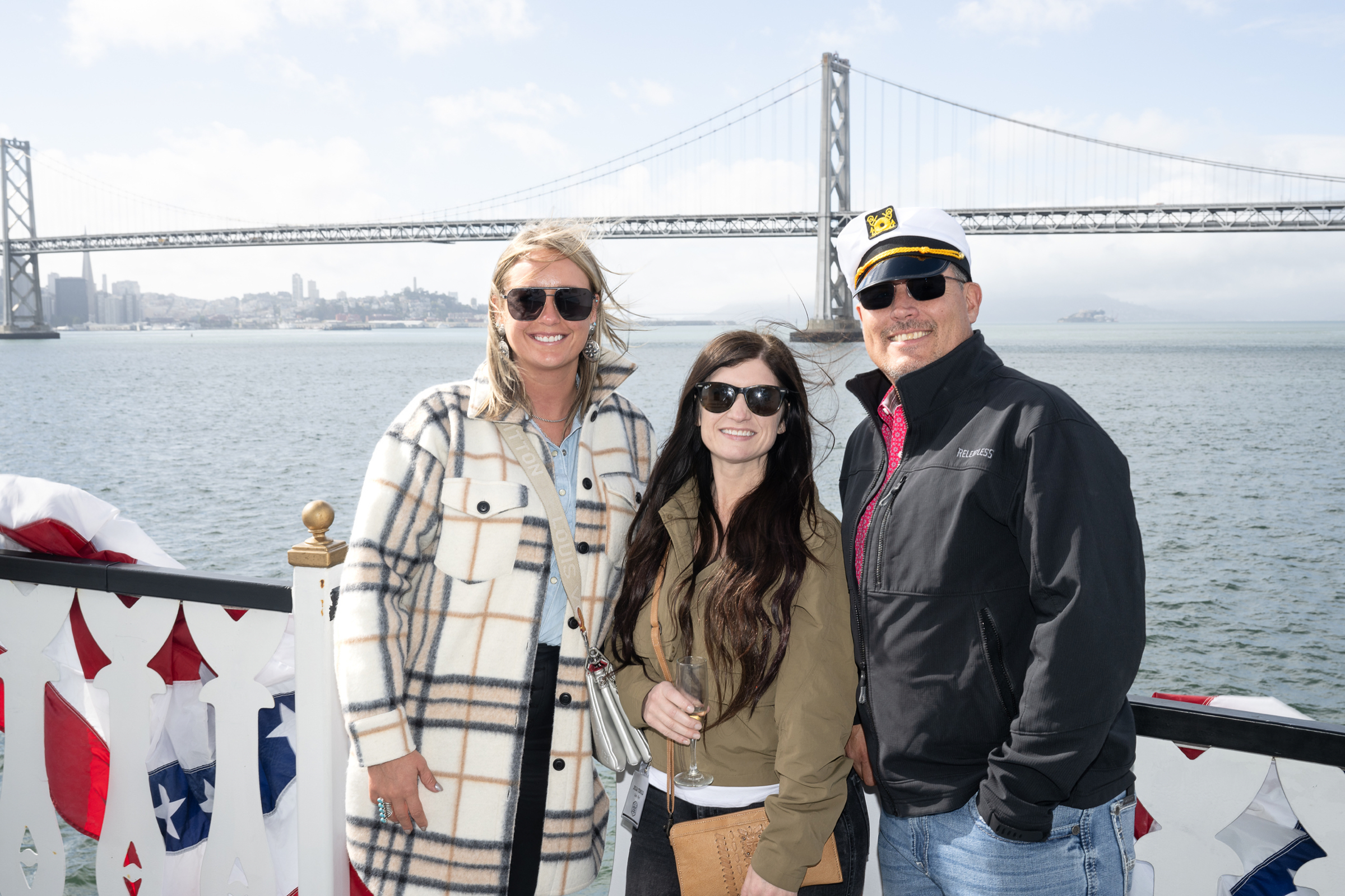 Guests on deck with a bridge and bay behind them