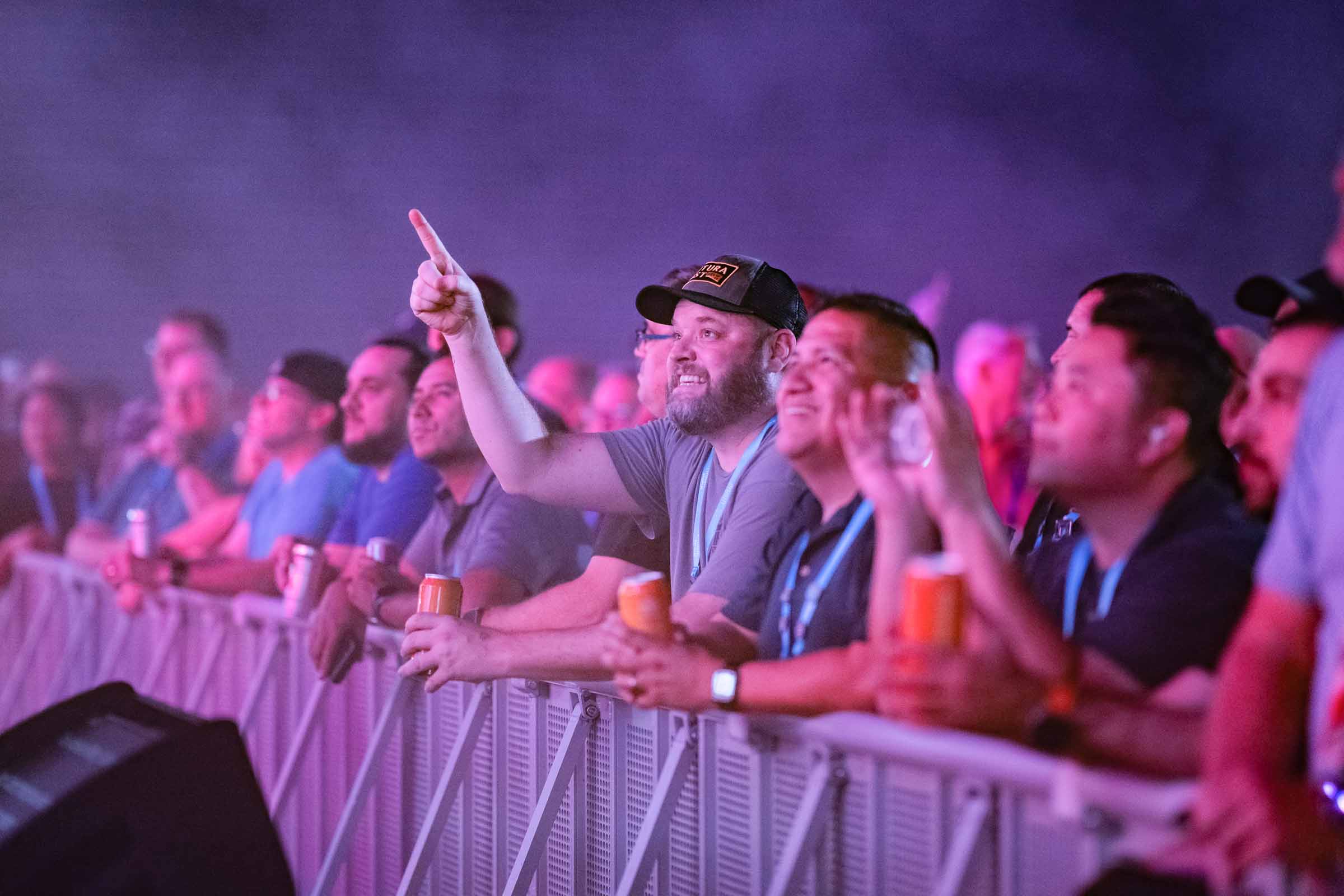 Group of engaged attendees cheering with drinks at neon-lit evening event