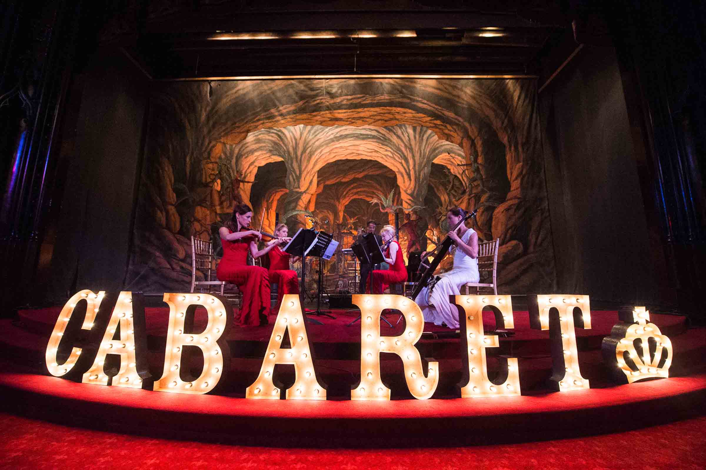 Live cabaret performance with orchestra on stage and illuminated signage
