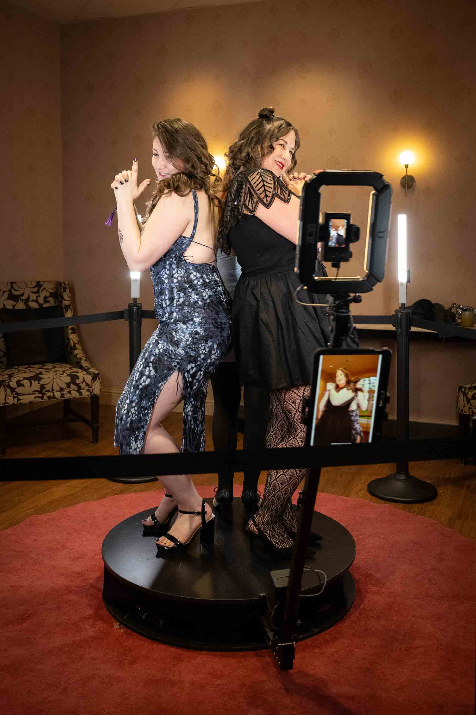 Two women pose playfully at an interactive digital mirror installation with dramatic off-camera lighting