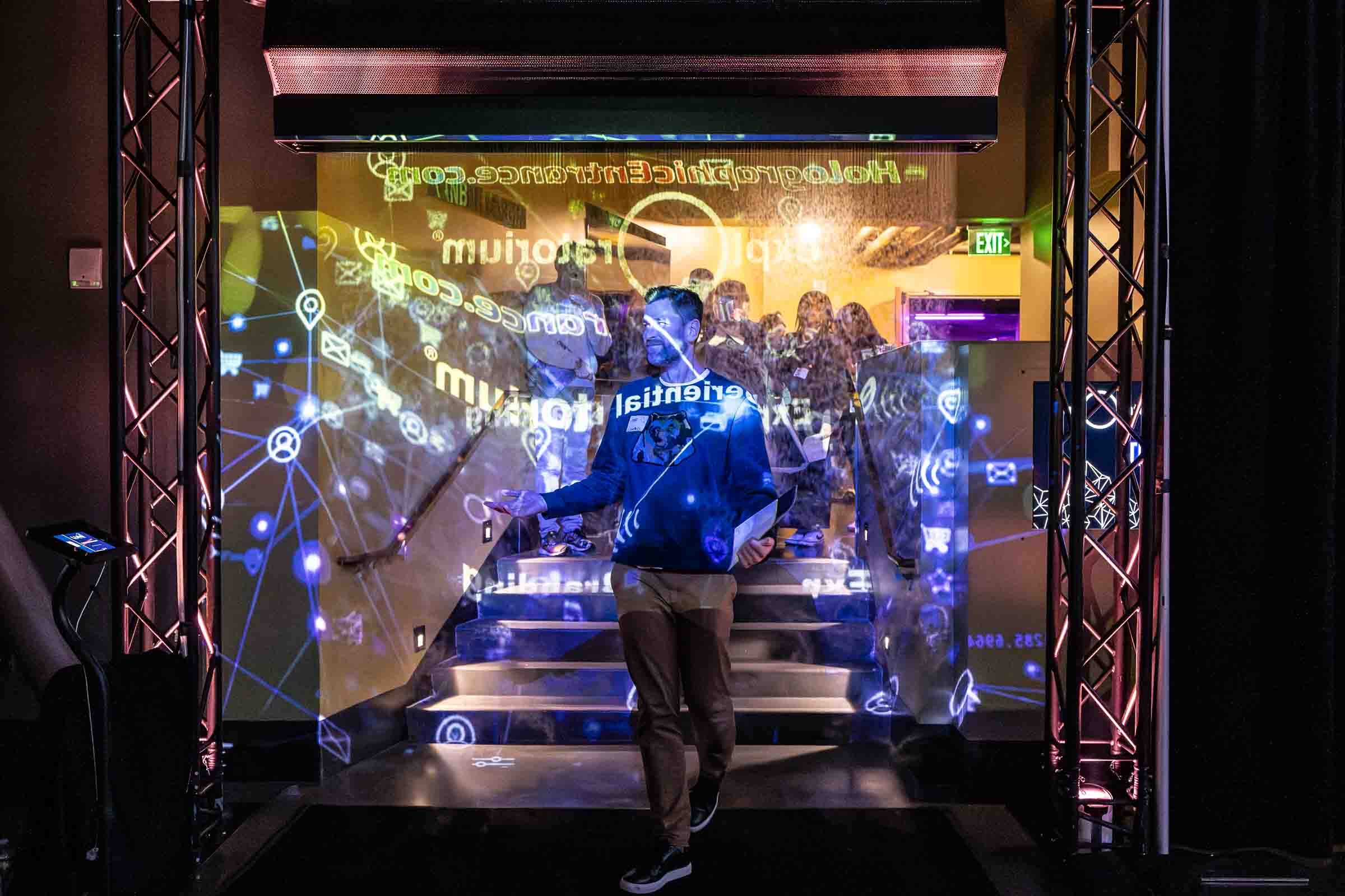 Person standing before technology display with blue projection mapping and digital motion graphics