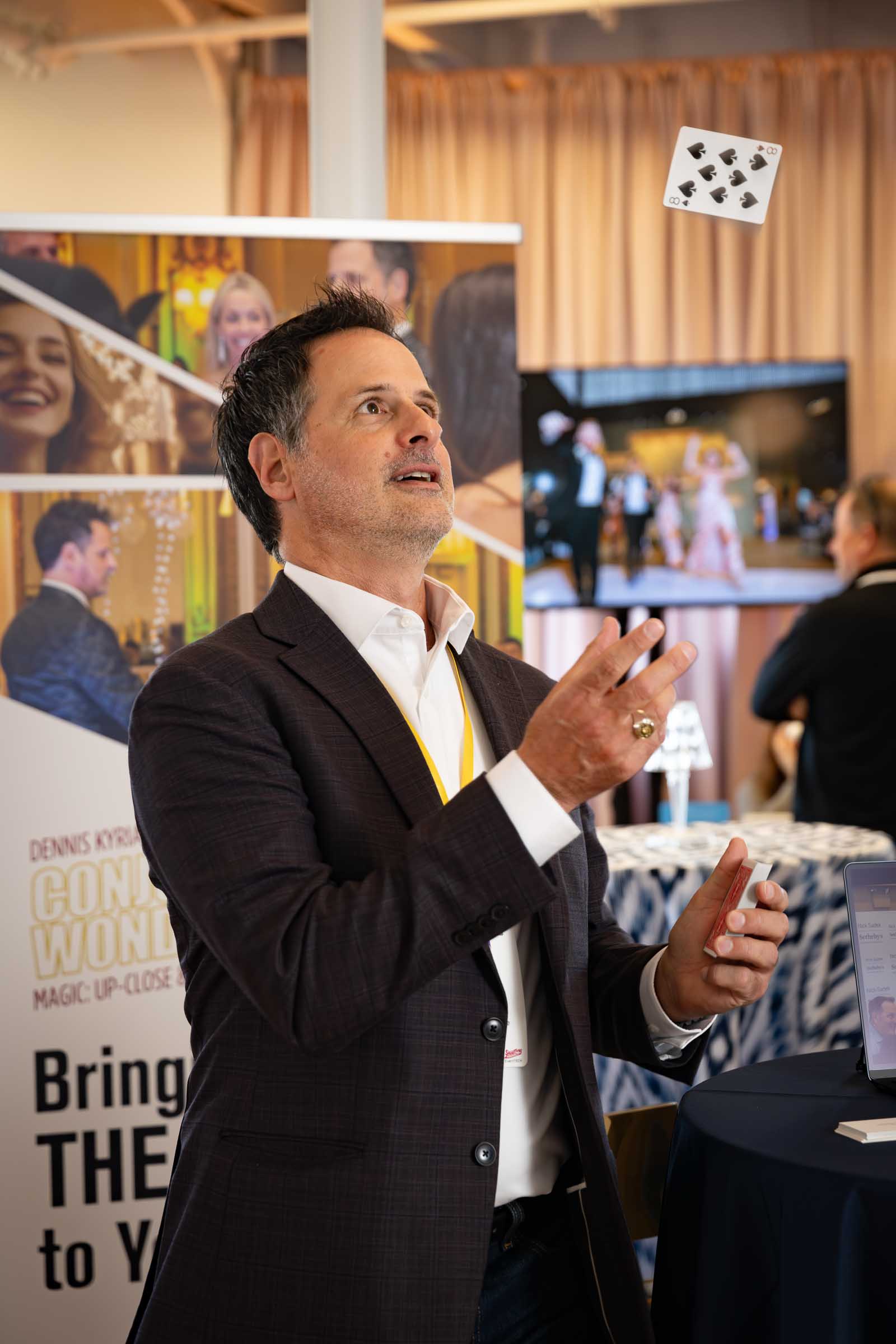 Man in business suit speaking with animated hand gestures at vendor showcase event