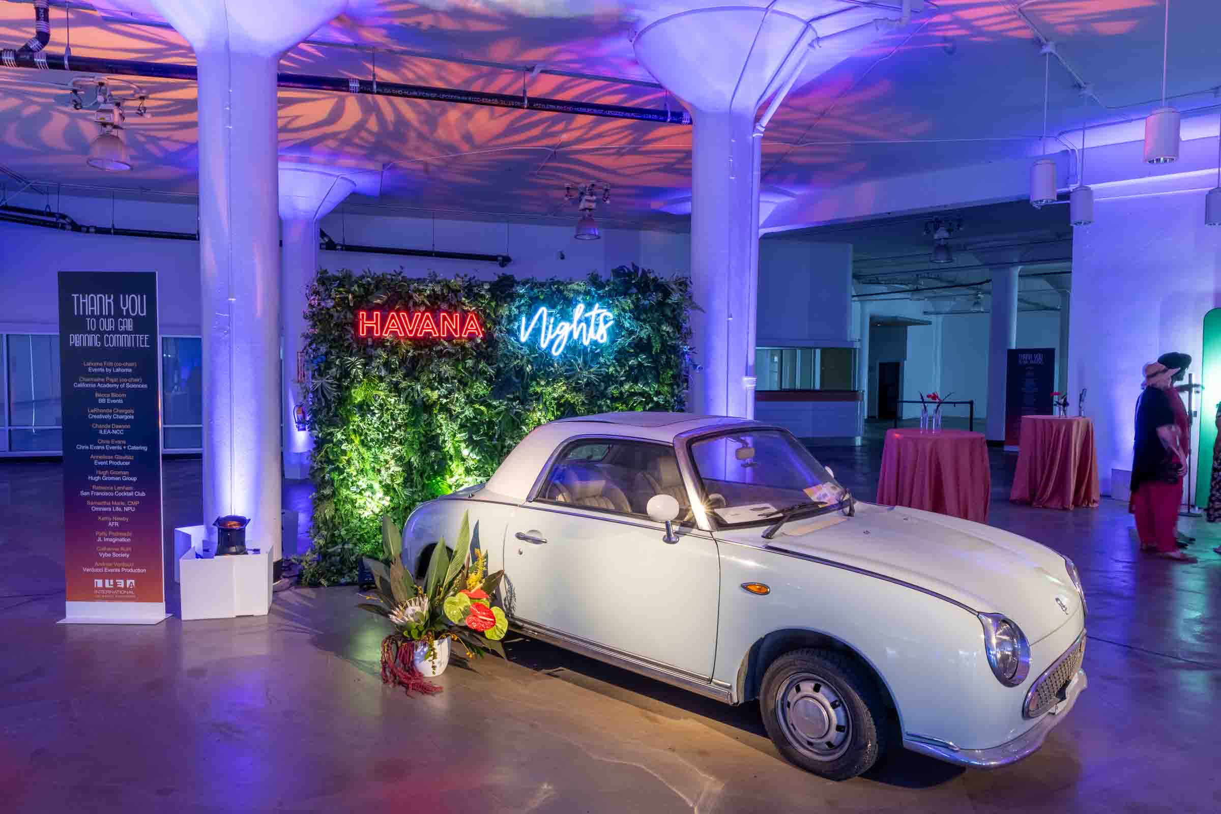 White vintage car display in front of lush green living wall with neon Havana Nights signage