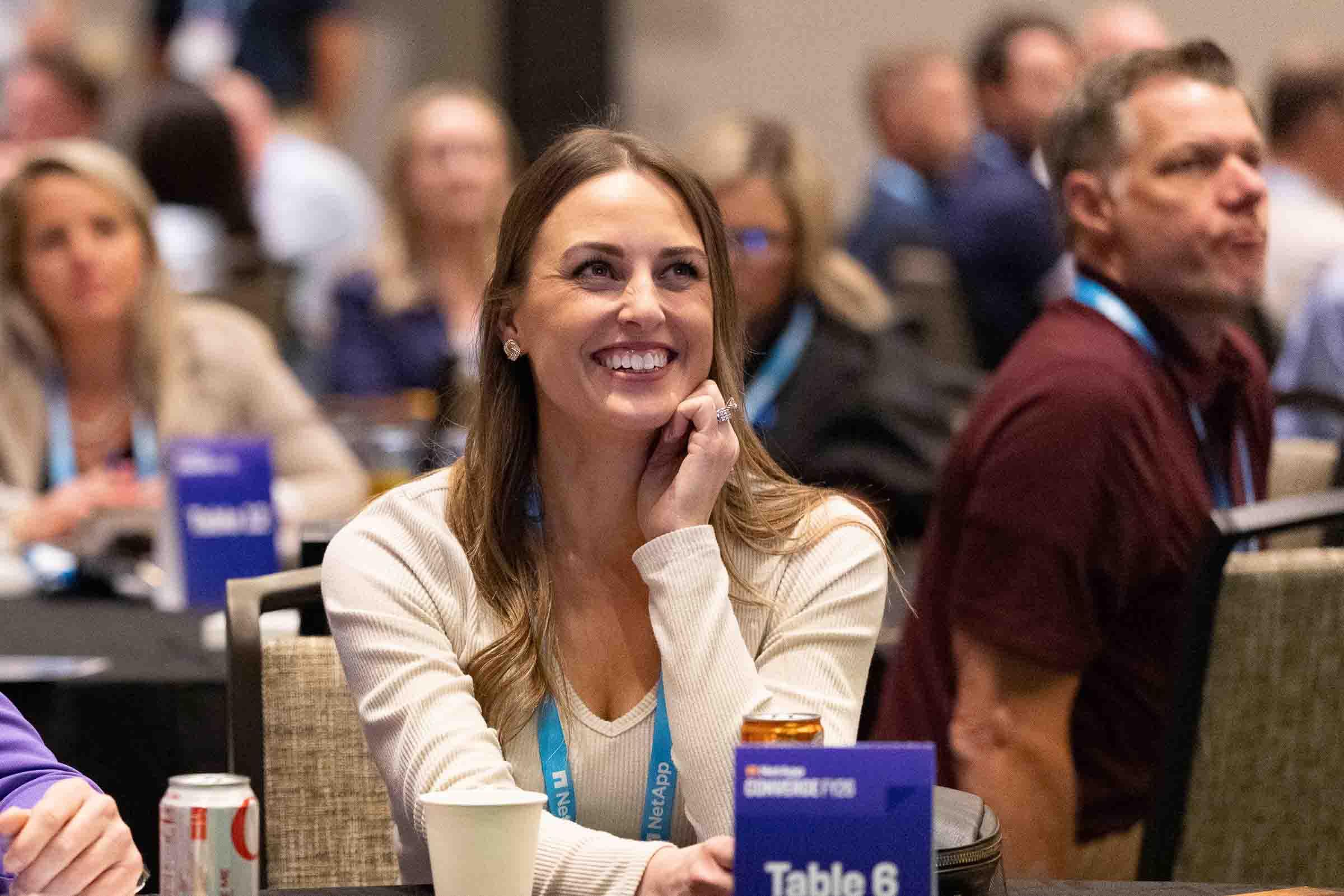 Conference attendee smiling during breakout session with table signage visible