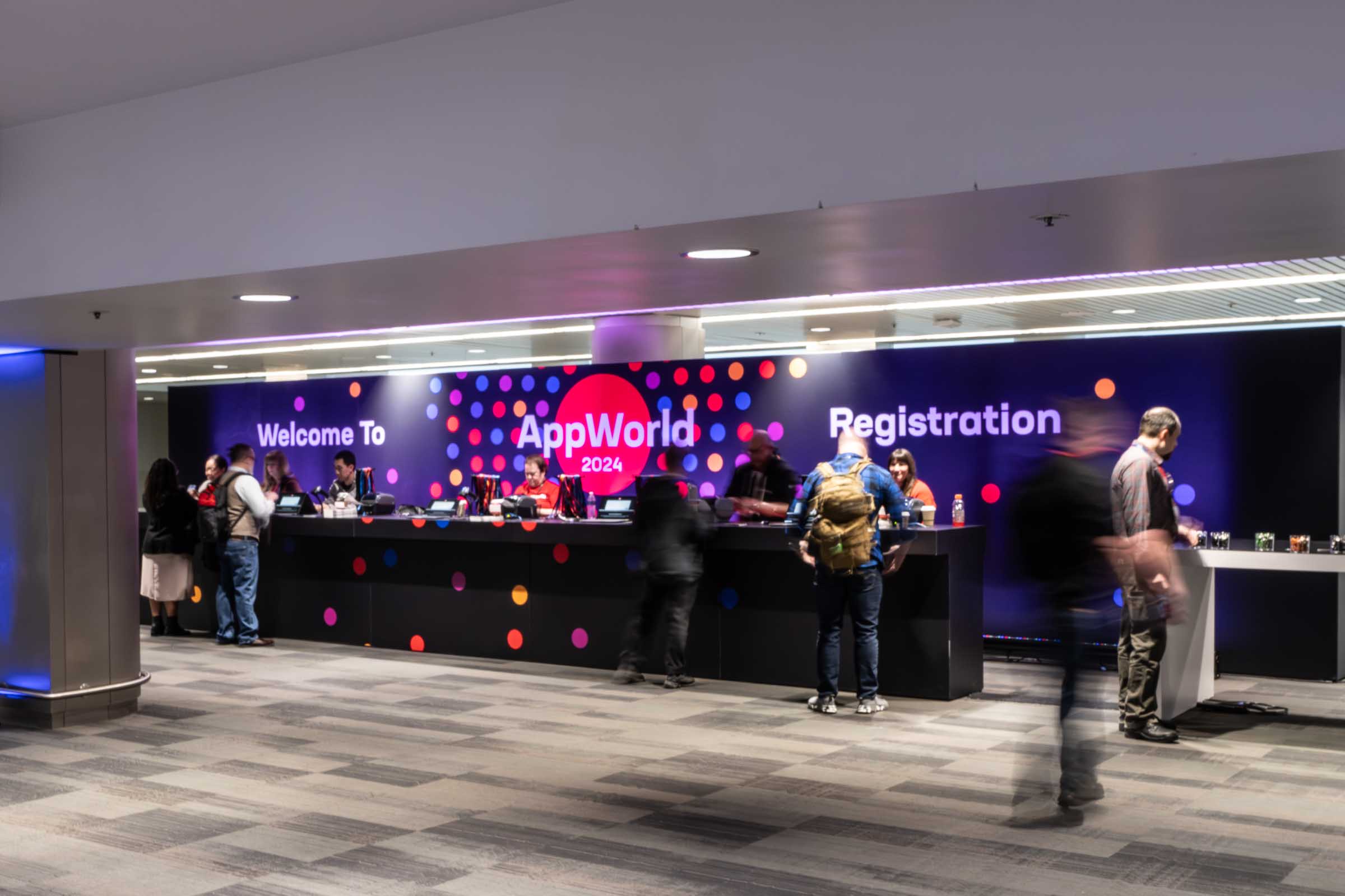 Registration booth with AppWorld 2024 branding and multiple attendees checking in