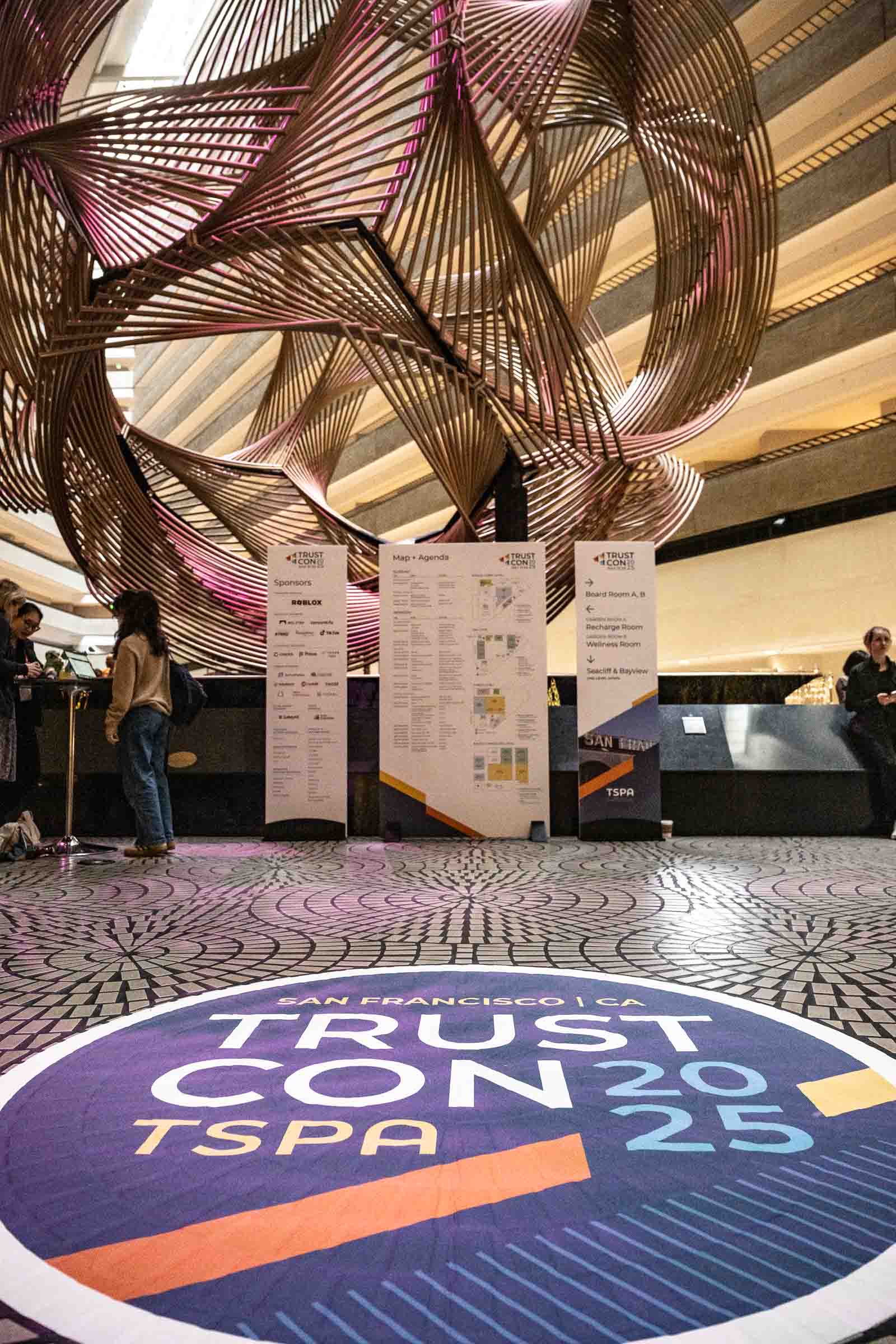 Modern conference venue with branded floor signage and artistic overhead installation