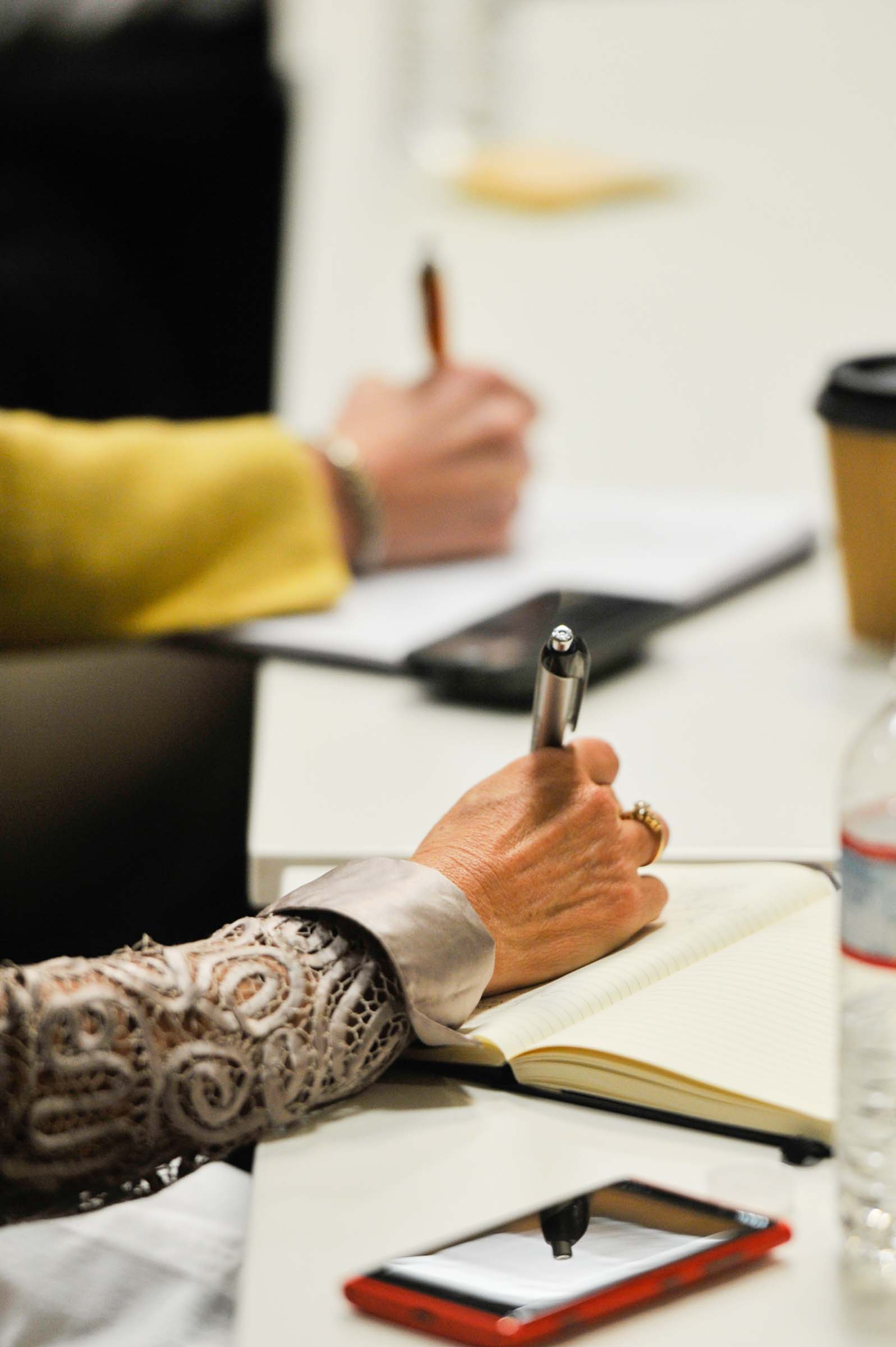 Close-up of attendee hands taking notes during conference workshop or breakout session
