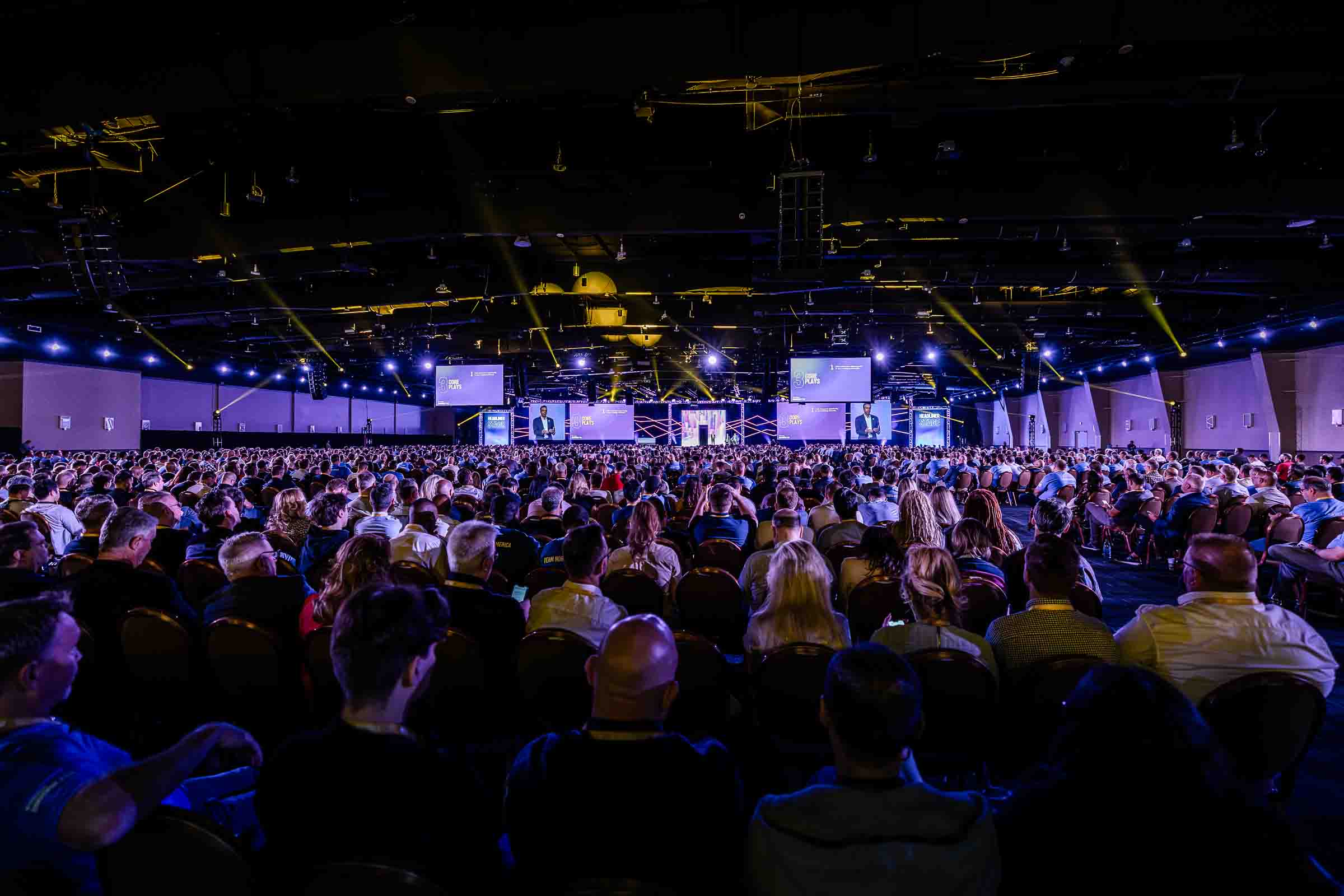 Large conference audience attending keynote presentation with stage screens visible