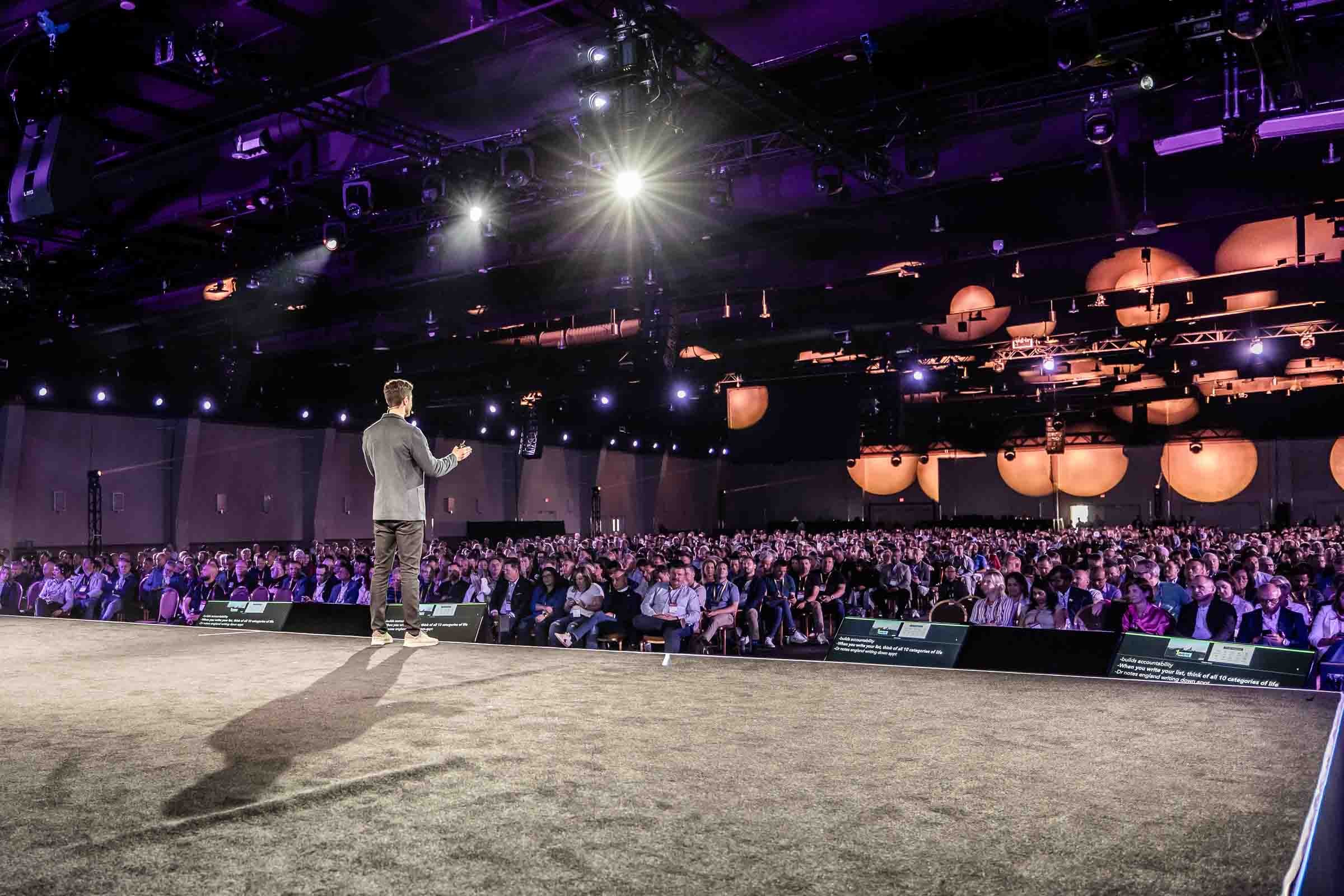 Single keynote speaker presenting to large seated audience in main conference ballroom