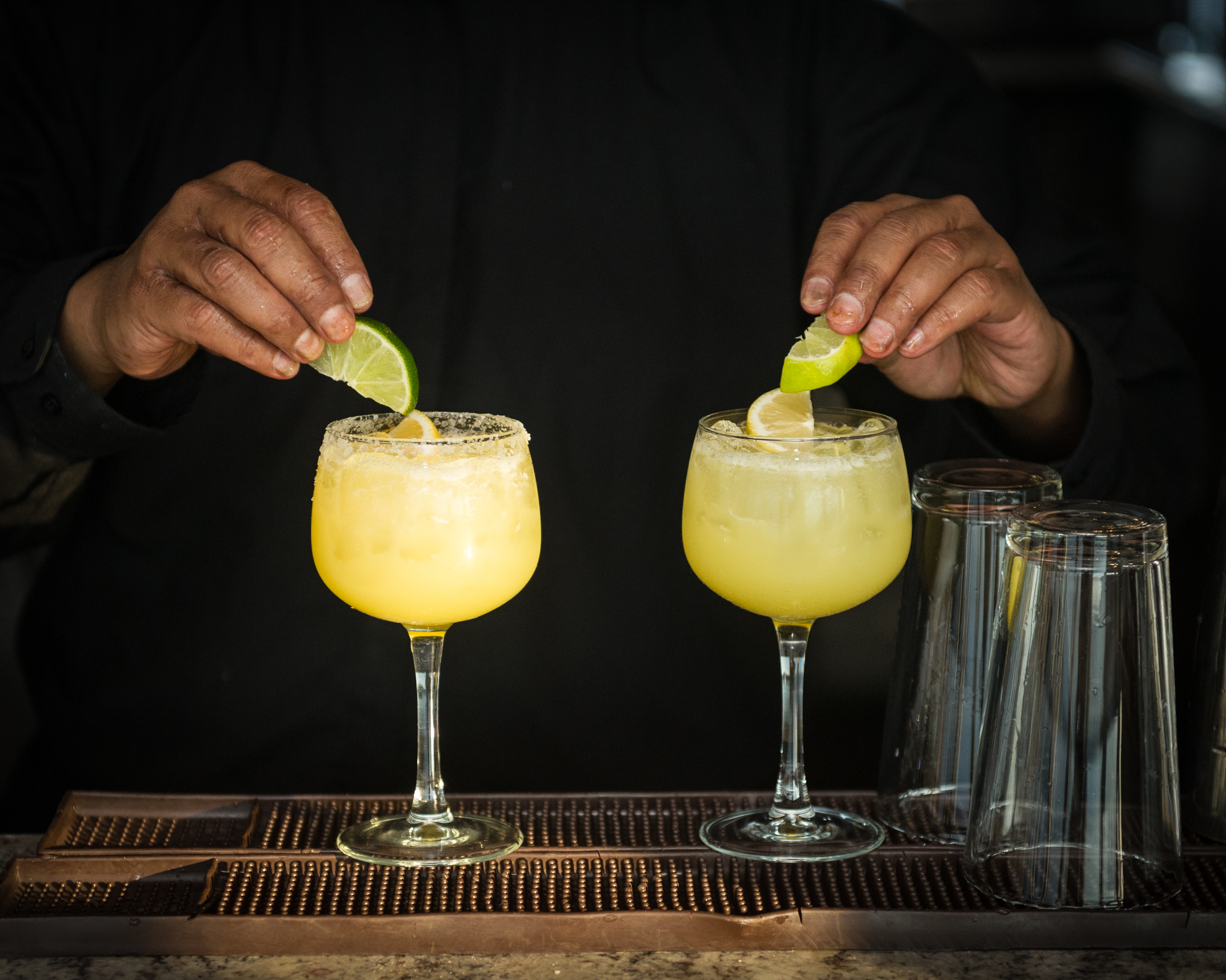 Bartender garnishing cocktails at an event bar, engaged in the work
