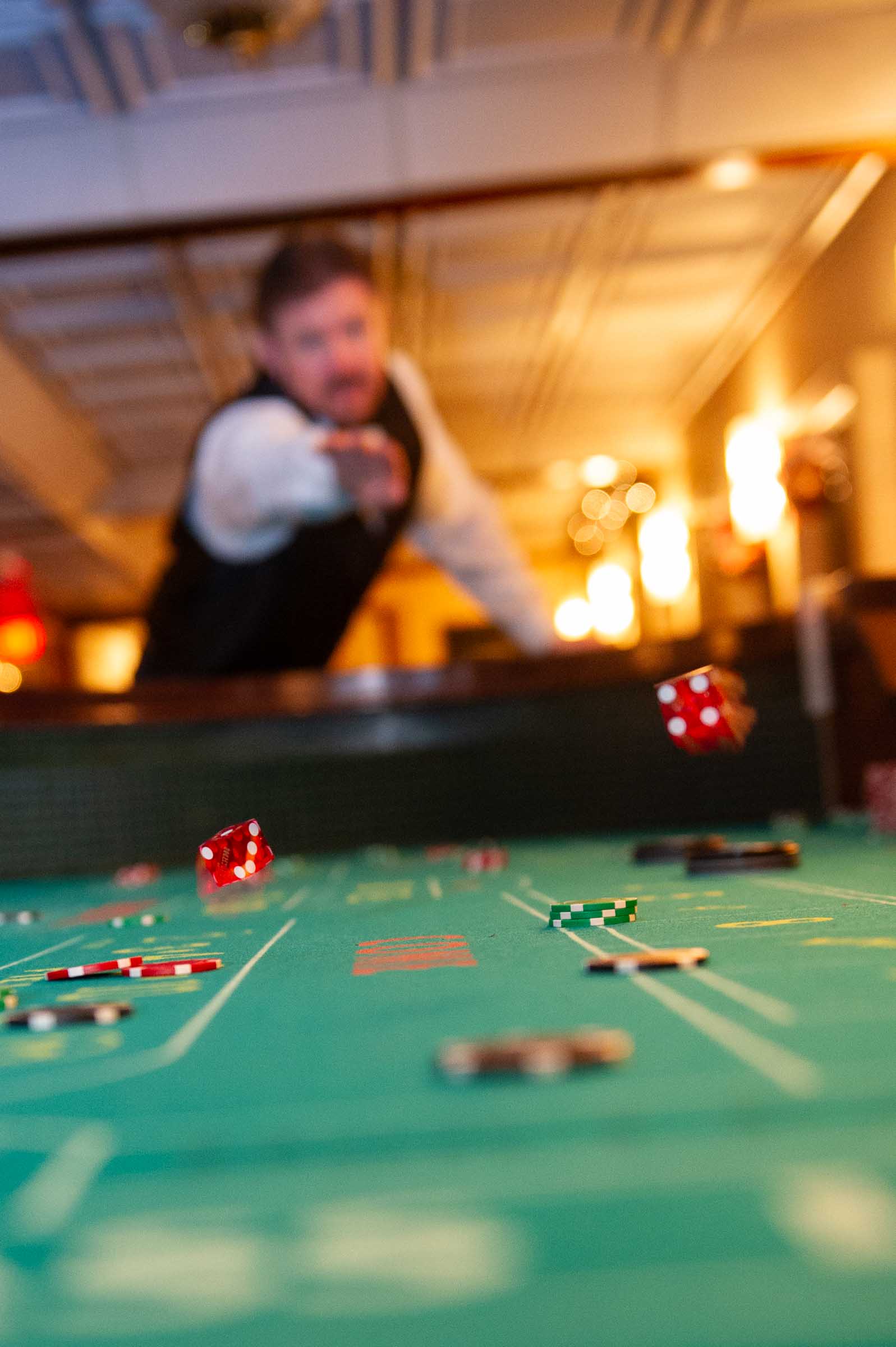 Casino gaming table with dice in foreground and blurred player in background