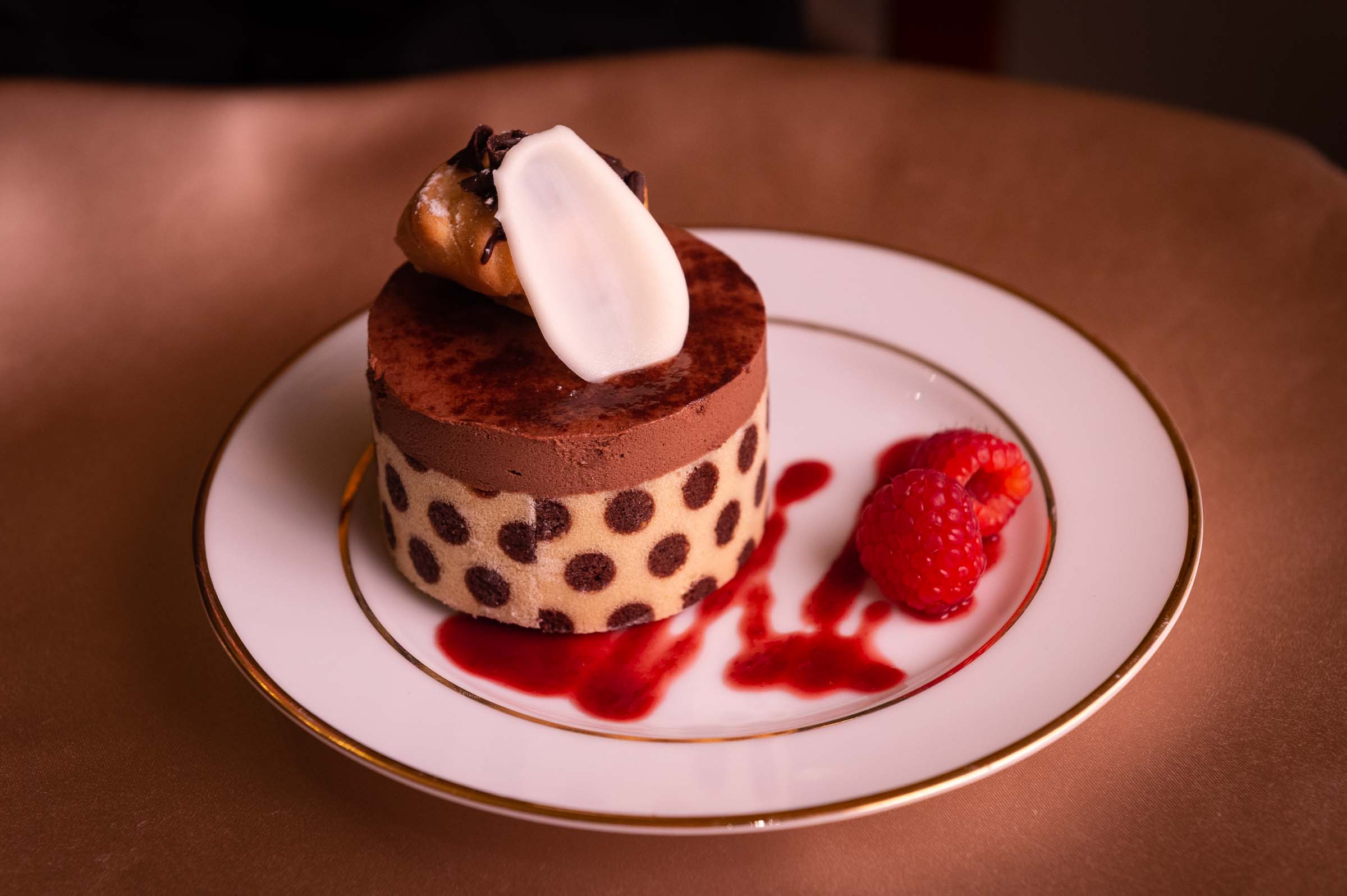 Decadent layered chocolate torte with polka dot pattern and cream topping on elegant dessert plate