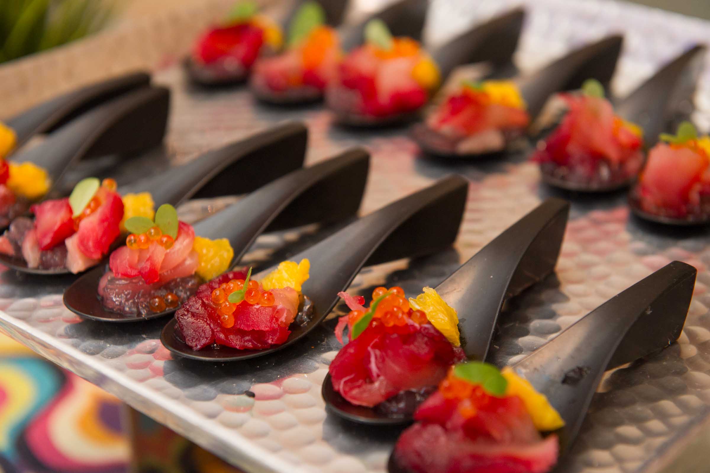 Artfully plated gourmet appetizers with fresh berries and colorful toppings on black spoons