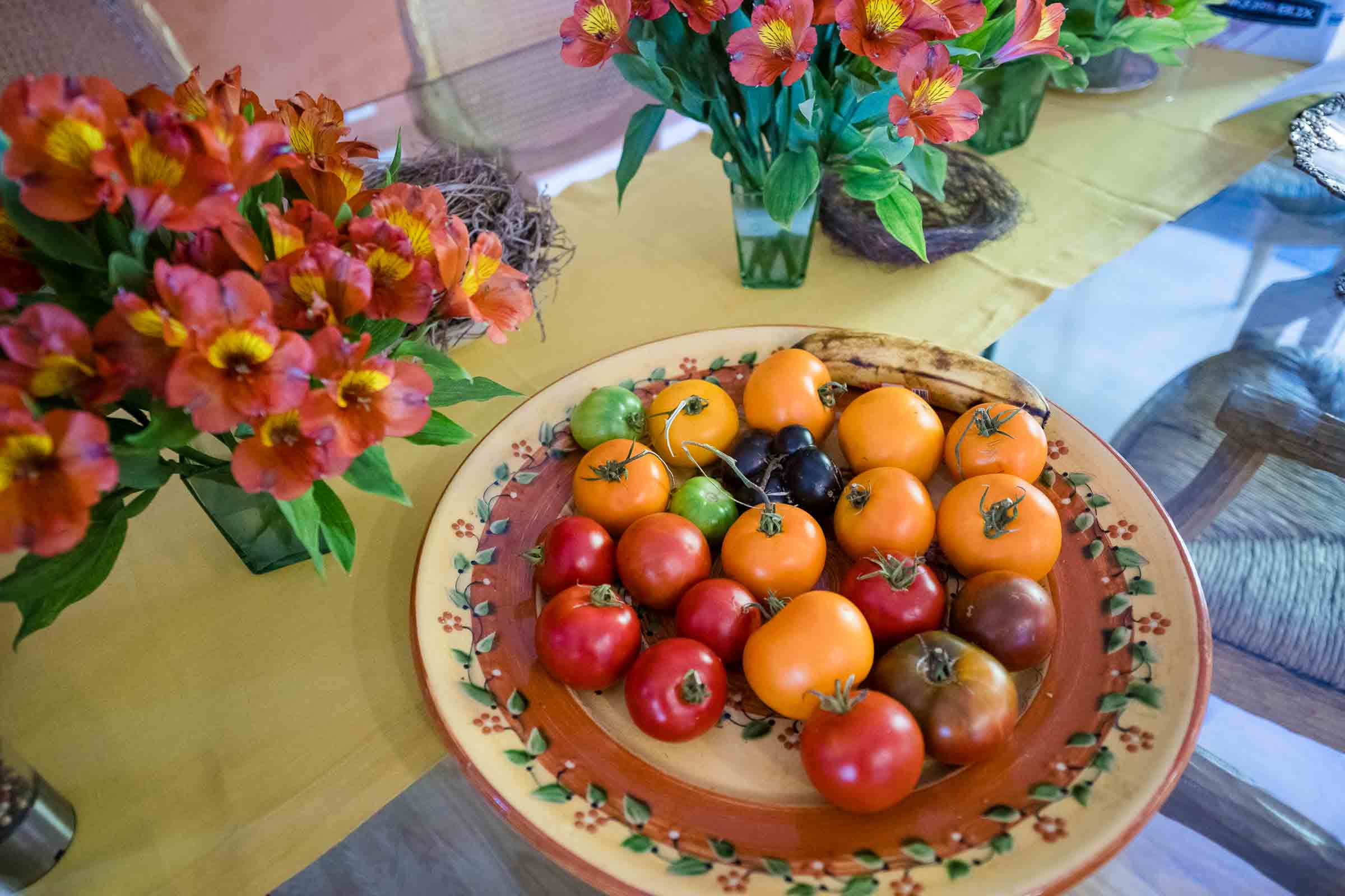 Decorative table setting with vibrant red and pink flowers in vases alongside fresh fruit display