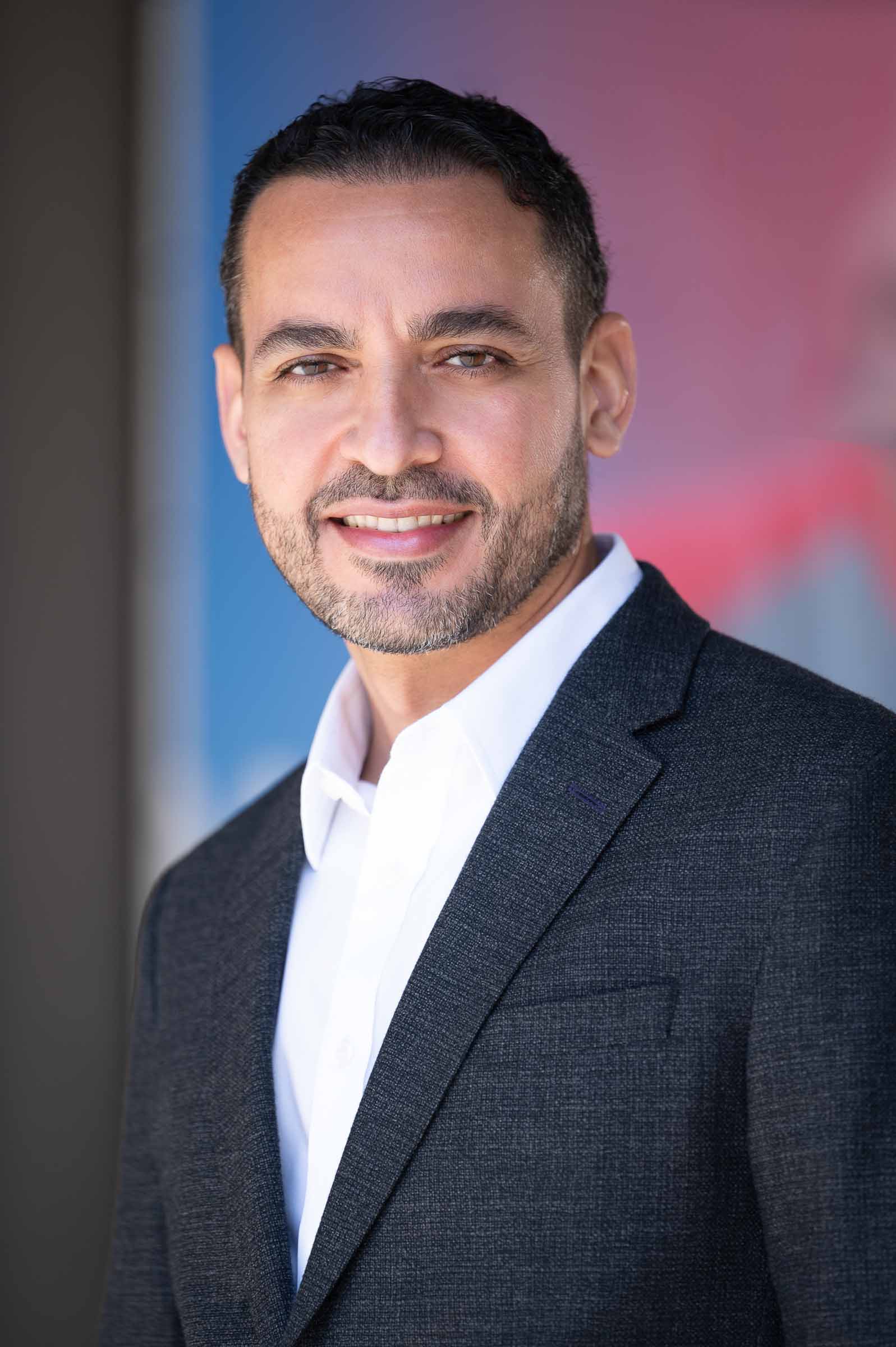 Professional headshot with blue and pink gradient backdrop