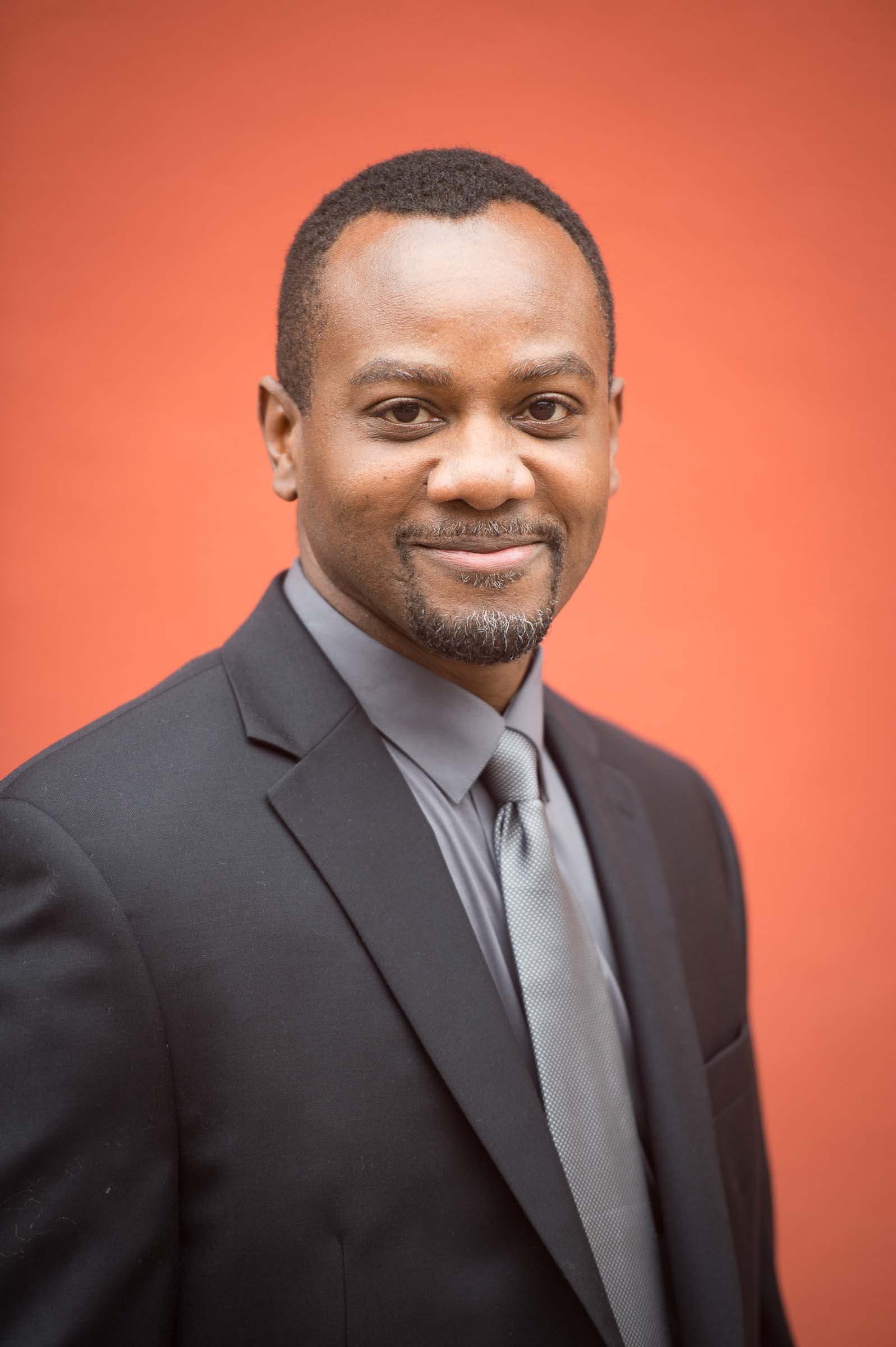 Professional portrait against coral-colored background