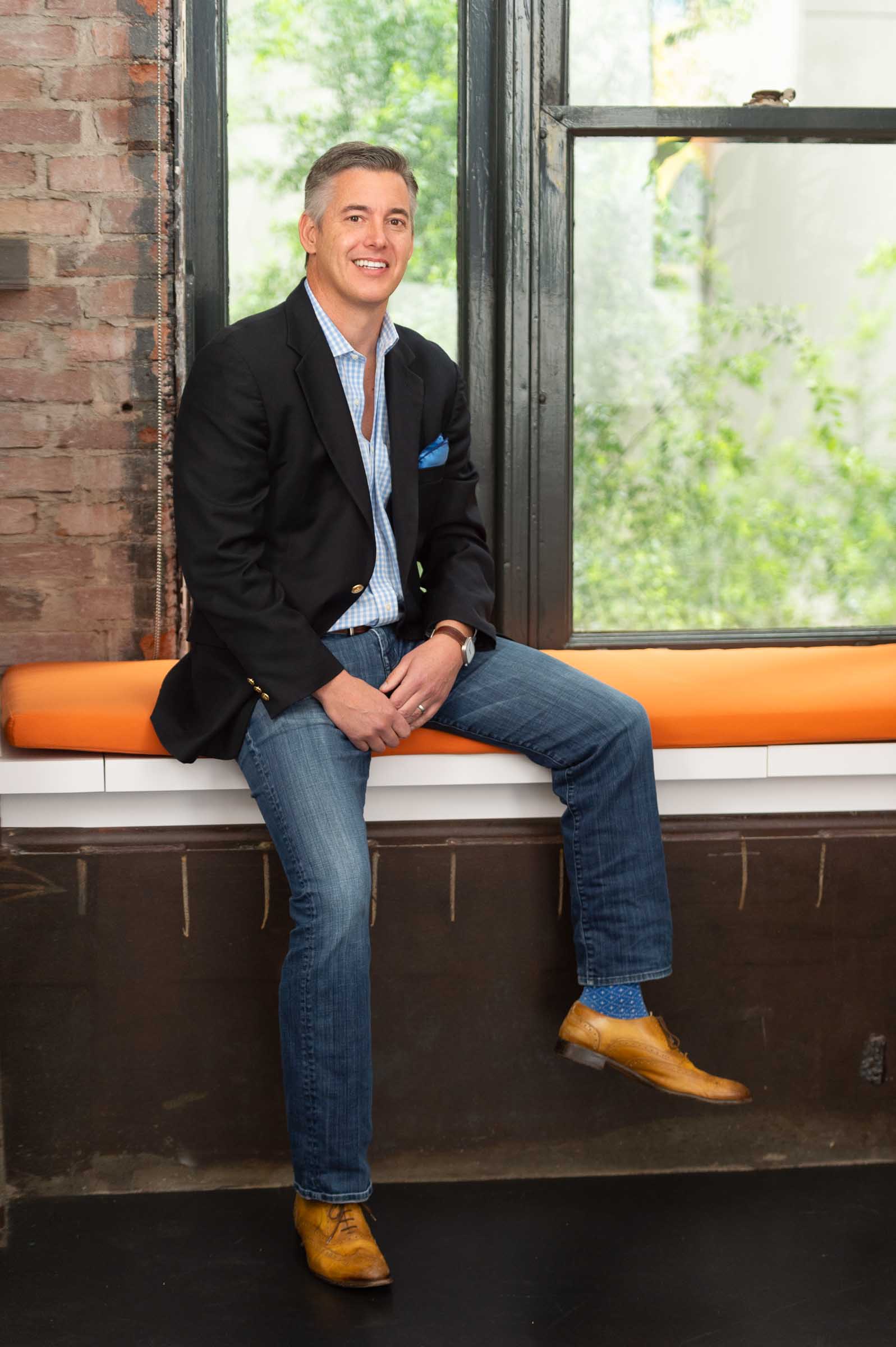 Executive seated near window with natural light creating dimensional portrait